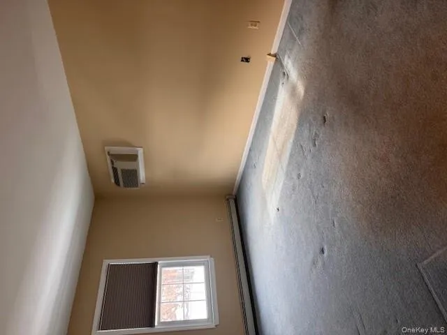 Empty room featuring a baseboard heating unit, carpet flooring, and an AC wall unit Empty room featuring a baseboard heating unit, carpet flooring, and an AC wall unit