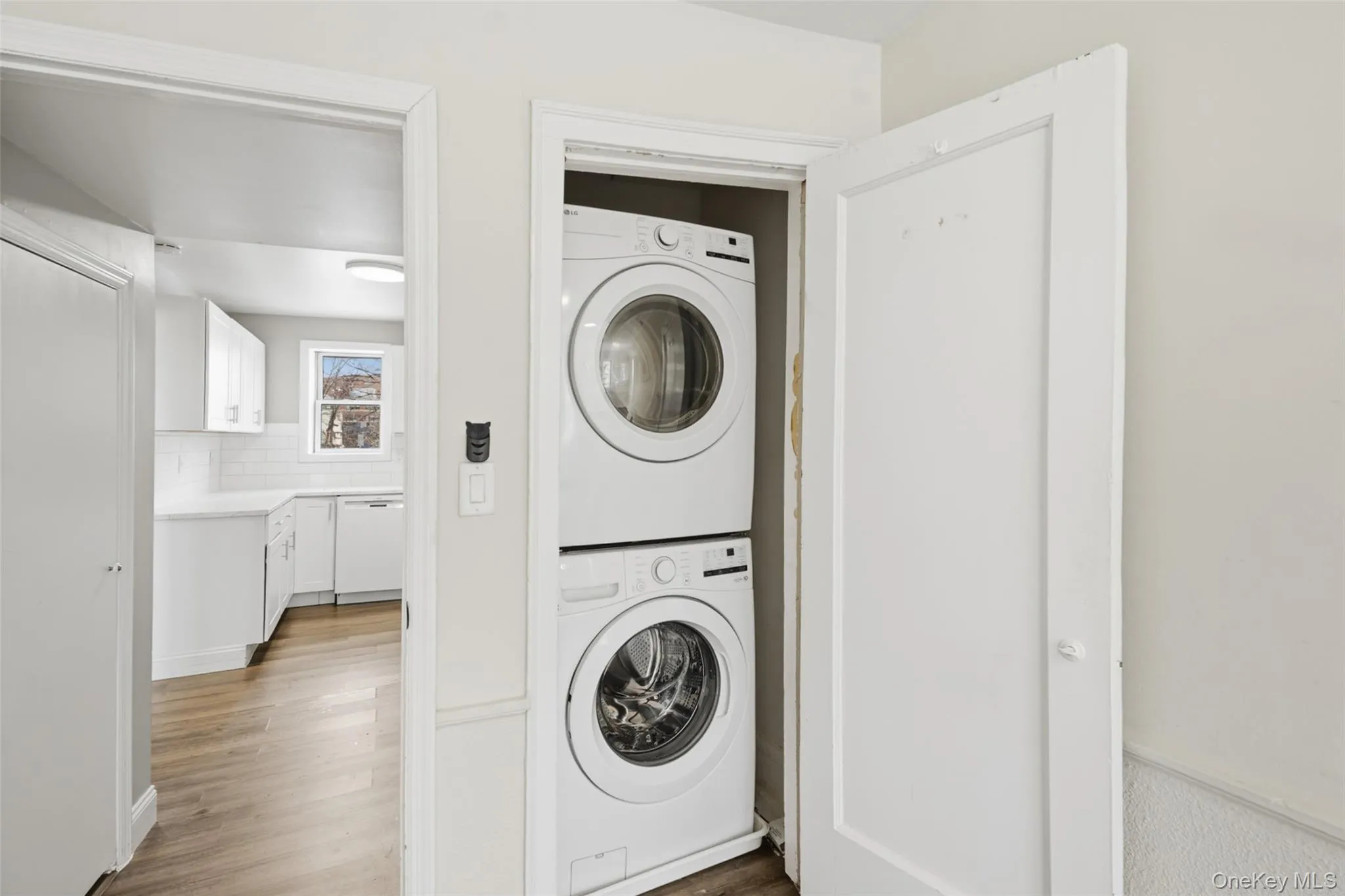 Laundry area featuring stacked washer and clothes dryer and wood finished floors Laundry area featuring stacked washer and clothes dryer and wood finished floors