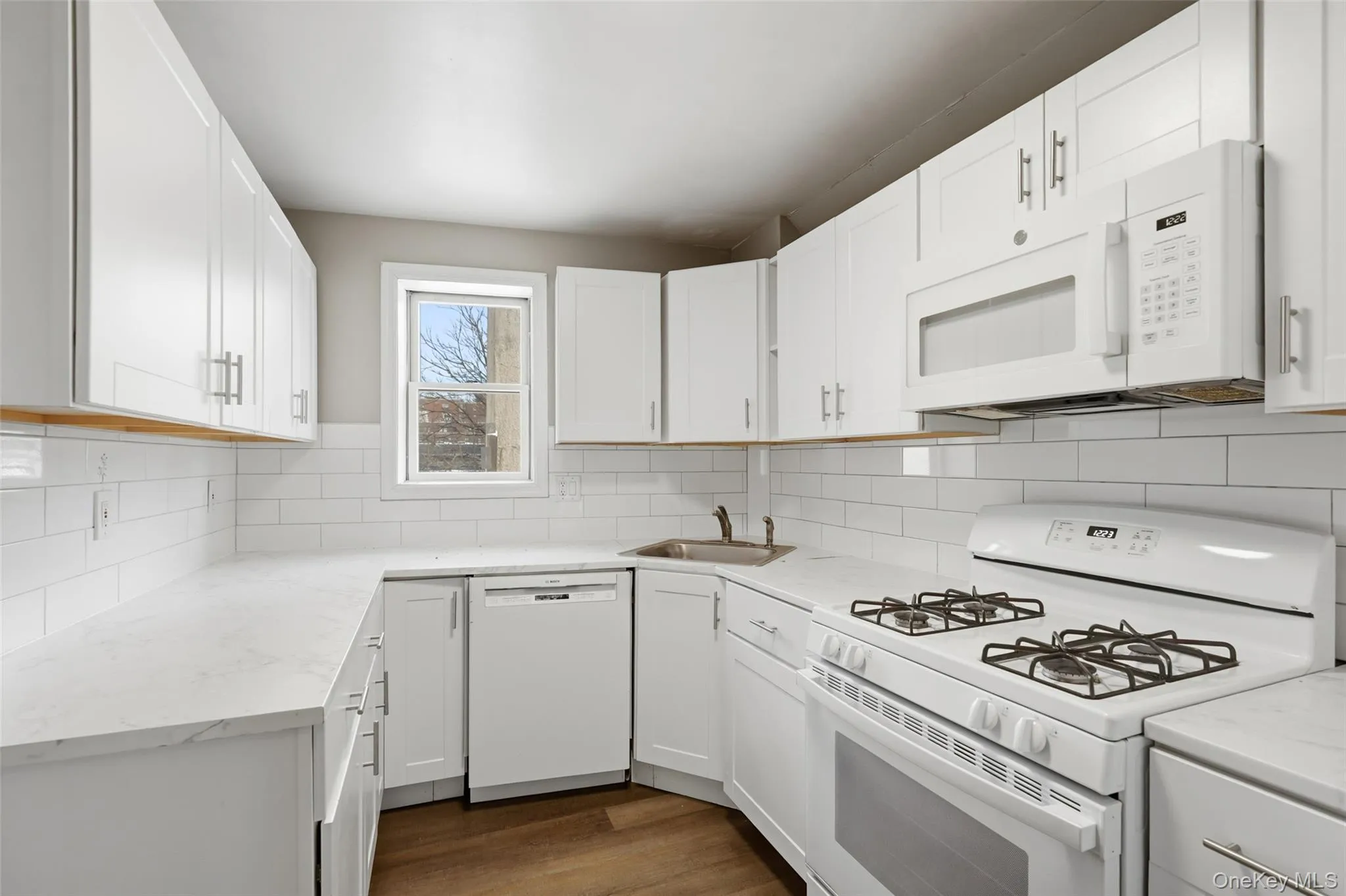 Kitchen featuring white appliances, decorative backsplash, and white cabinetry Kitchen featuring white appliances, decorative backsplash, and white cabinetry