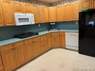 Kitchen with black appliances, light countertops, and brown cabinets Kitchen with black appliances, light countertops, and brown cabinets