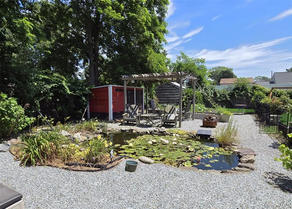 View of yard featuring a patio area, a pergola, a small pond, and an outdoor fire pit View of yard featuring a patio area, a pergola, a small pond, and an outdoor fire pit