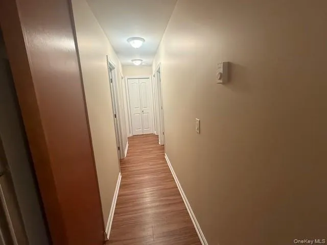 Corridor with baseboards and wood finished floors Corridor with baseboards and wood finished floors