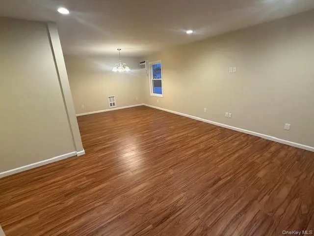 Unfurnished room featuring recessed lighting, dark wood-type flooring, and a chandelier Unfurnished room featuring recessed lighting, dark wood-type flooring, and a chandelier