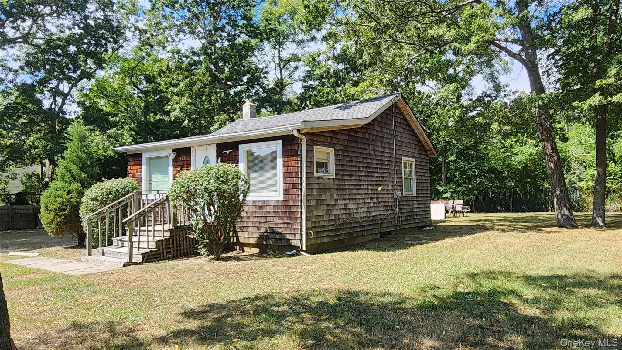 View of front facade featuring a front lawn, a chimney, roof with shingles, and view of scattered trees View of front facade featuring a front lawn, a chimney, roof with shingles, and view of scattered trees