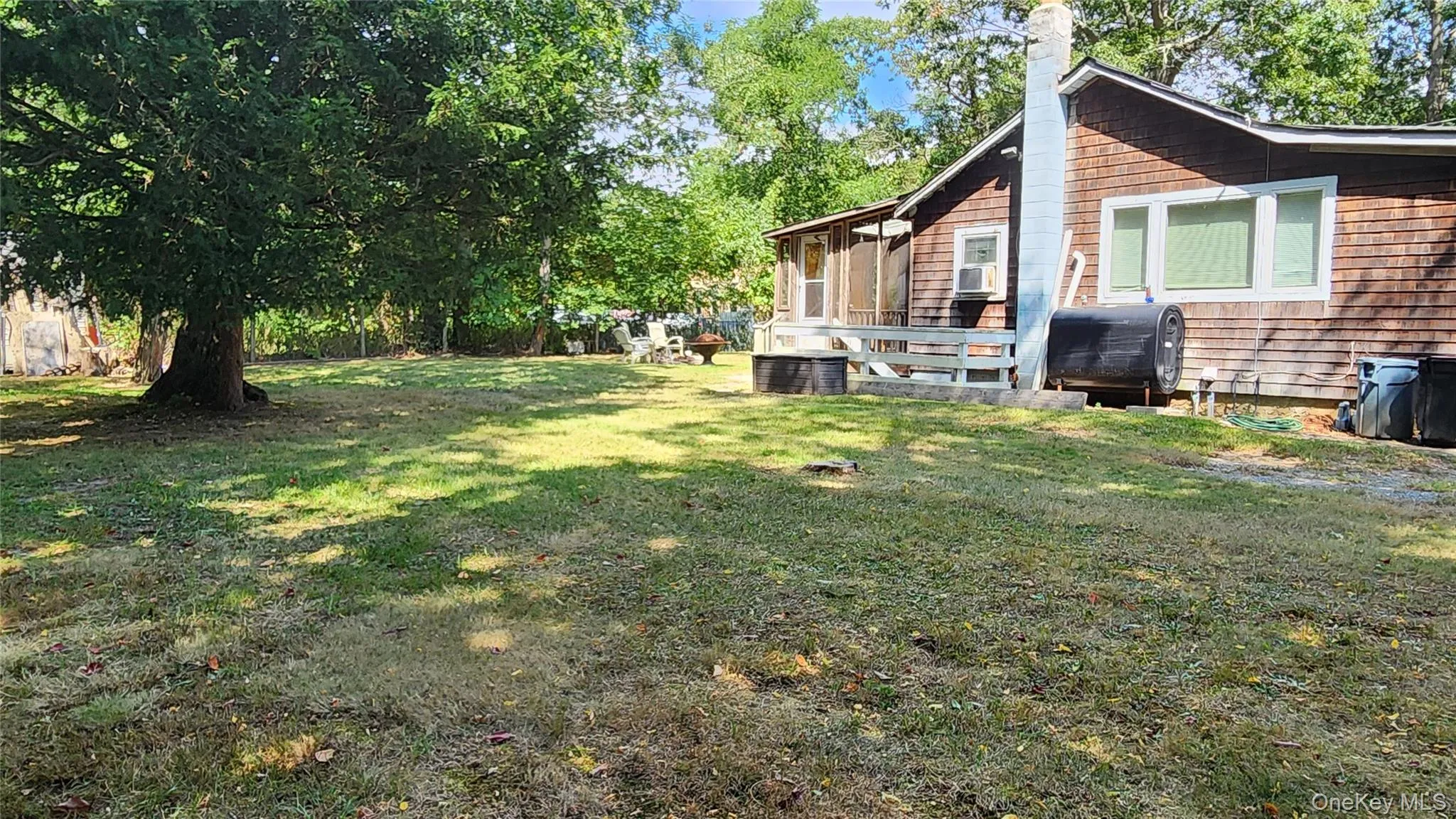 View of grassy yard featuring oil tank and view of wooded area View of grassy yard featuring oil tank and view of wooded area