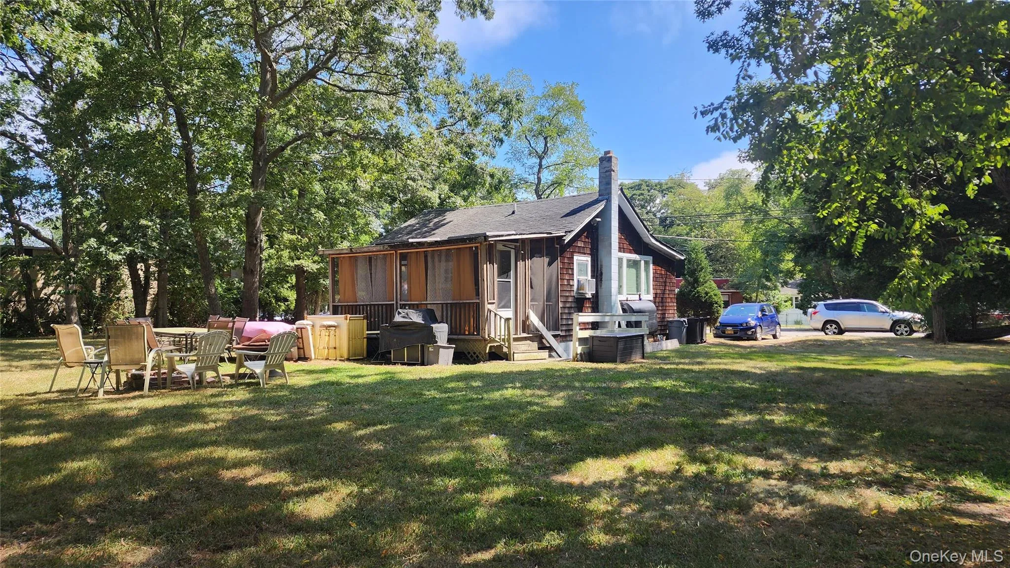 Back of property with a lawn, a chimney, a sunroom, and view of scattered trees Back of property with a lawn, a chimney, a sunroom, and view of scattered trees