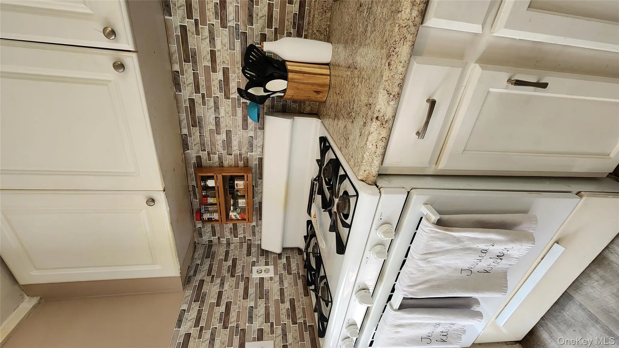 Kitchen with white range with gas cooktop, white cabinetry, and light stone countertops Kitchen with white range with gas cooktop, white cabinetry, and light stone countertops