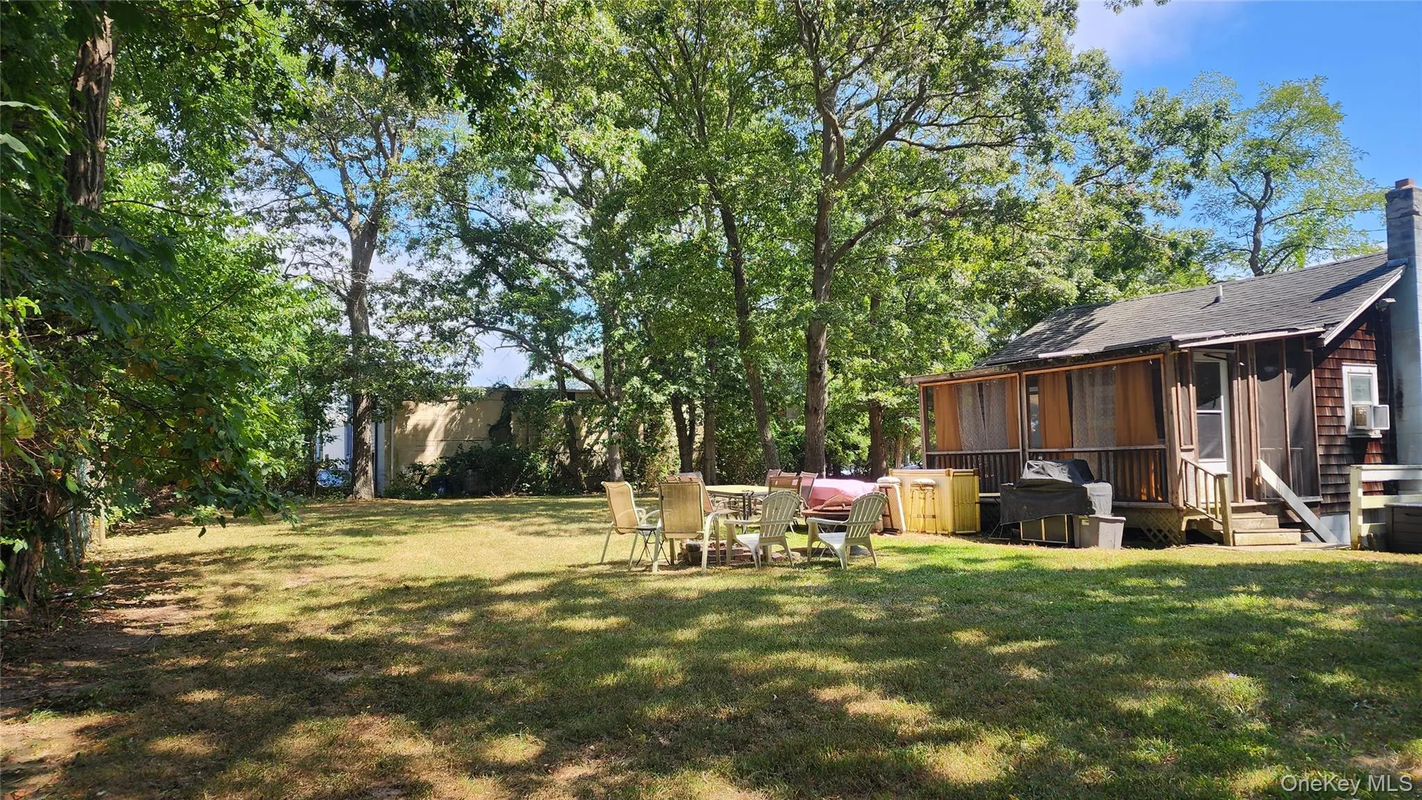 View of grassy yard featuring a deck and a sunroom View of grassy yard featuring a deck and a sunroom