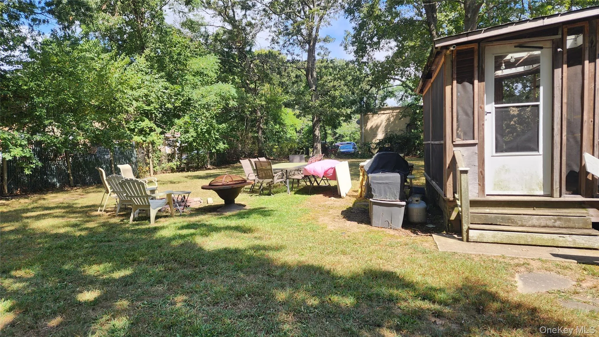 View of yard featuring entry steps, a fire pit, and view of scattered trees View of yard featuring entry steps, a fire pit, and view of scattered trees