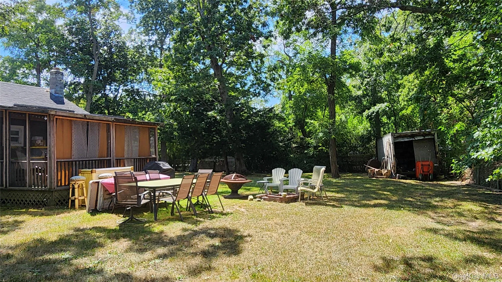 View of green lawn featuring a fire pit, a sunroom, a patio area, and a storage unit View of green lawn featuring a fire pit, a sunroom, a patio area, and a storage unit