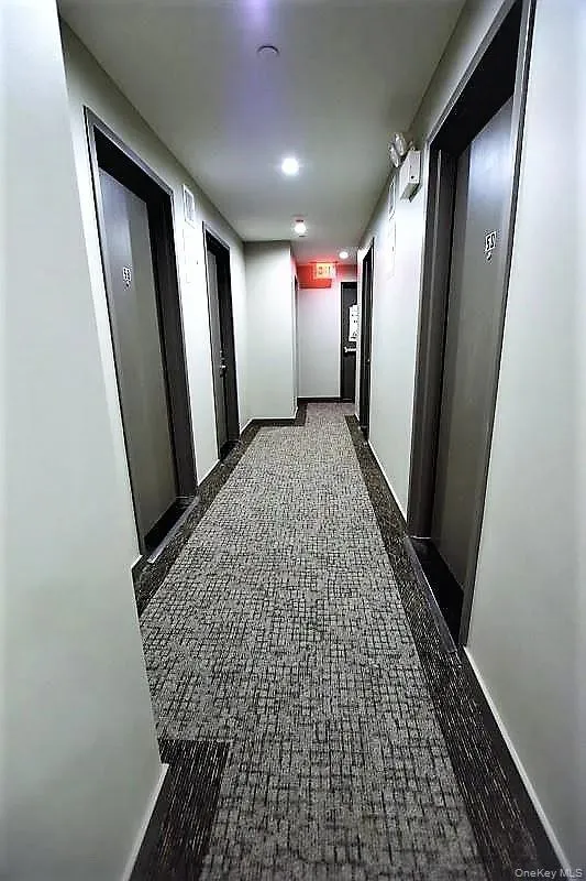 Corridor featuring baseboards and dark floors Corridor featuring baseboards and dark floors