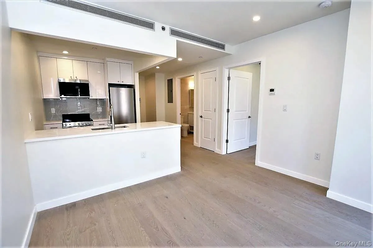 Kitchen with white cabinets, a peninsula, backsplash, appliances with stainless steel finishes, and light wood finished floors Kitchen with white cabinets, a peninsula, backsplash, appliances with stainless steel finishes, and light wood finished floors