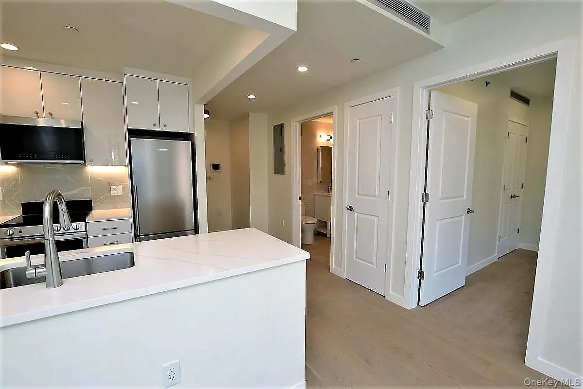 Kitchen with stainless steel appliances, recessed lighting, light wood-style flooring, tasteful backsplash, and light stone countertops Kitchen with stainless steel appliances, recessed lighting, light wood-style flooring, tasteful backsplash, and light stone countertops