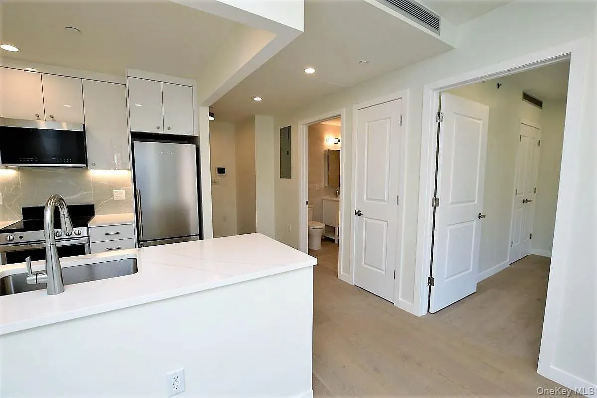 Kitchen with stainless steel appliances, recessed lighting, light wood-style flooring, decorative backsplash, and white cabinets Kitchen with stainless steel appliances, recessed lighting, light wood-style flooring, decorative backsplash, and white cabinets
