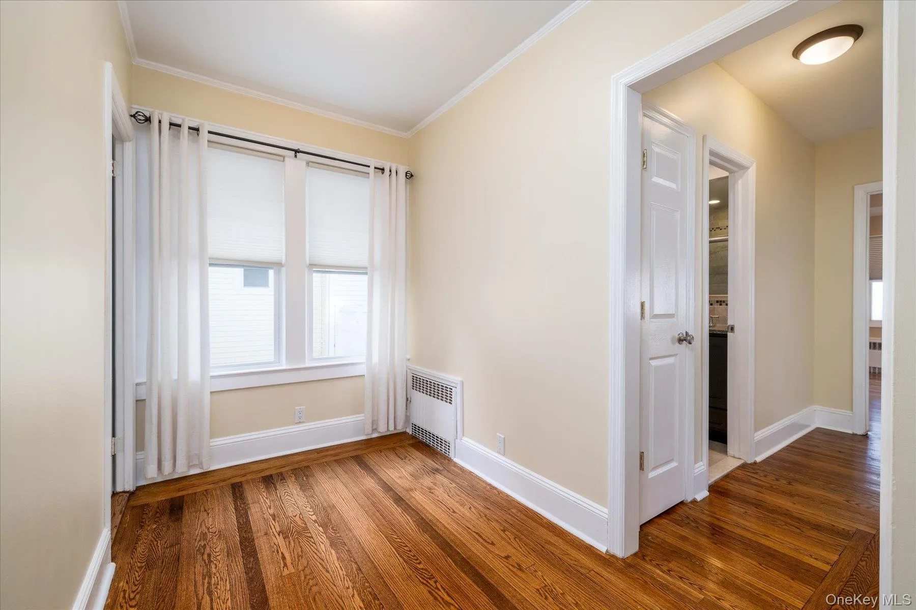 Unfurnished room with dark wood finished floors, radiator, and ornamental molding Unfurnished room with dark wood finished floors, radiator, and ornamental molding