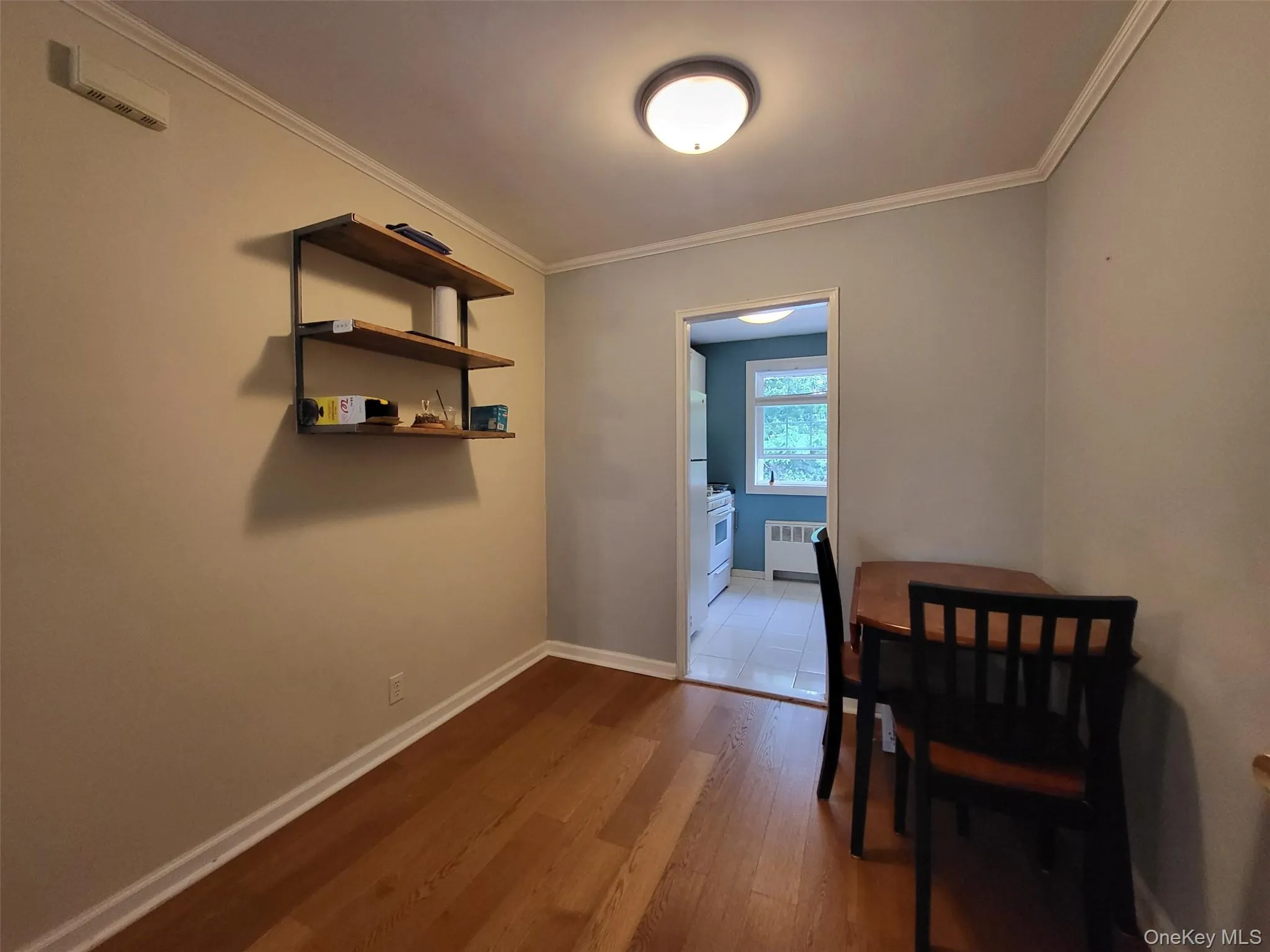 Dining area featuring radiator heating unit, wood finished floors, and ornamental molding Dining area featuring radiator heating unit, wood finished floors, and ornamental molding
