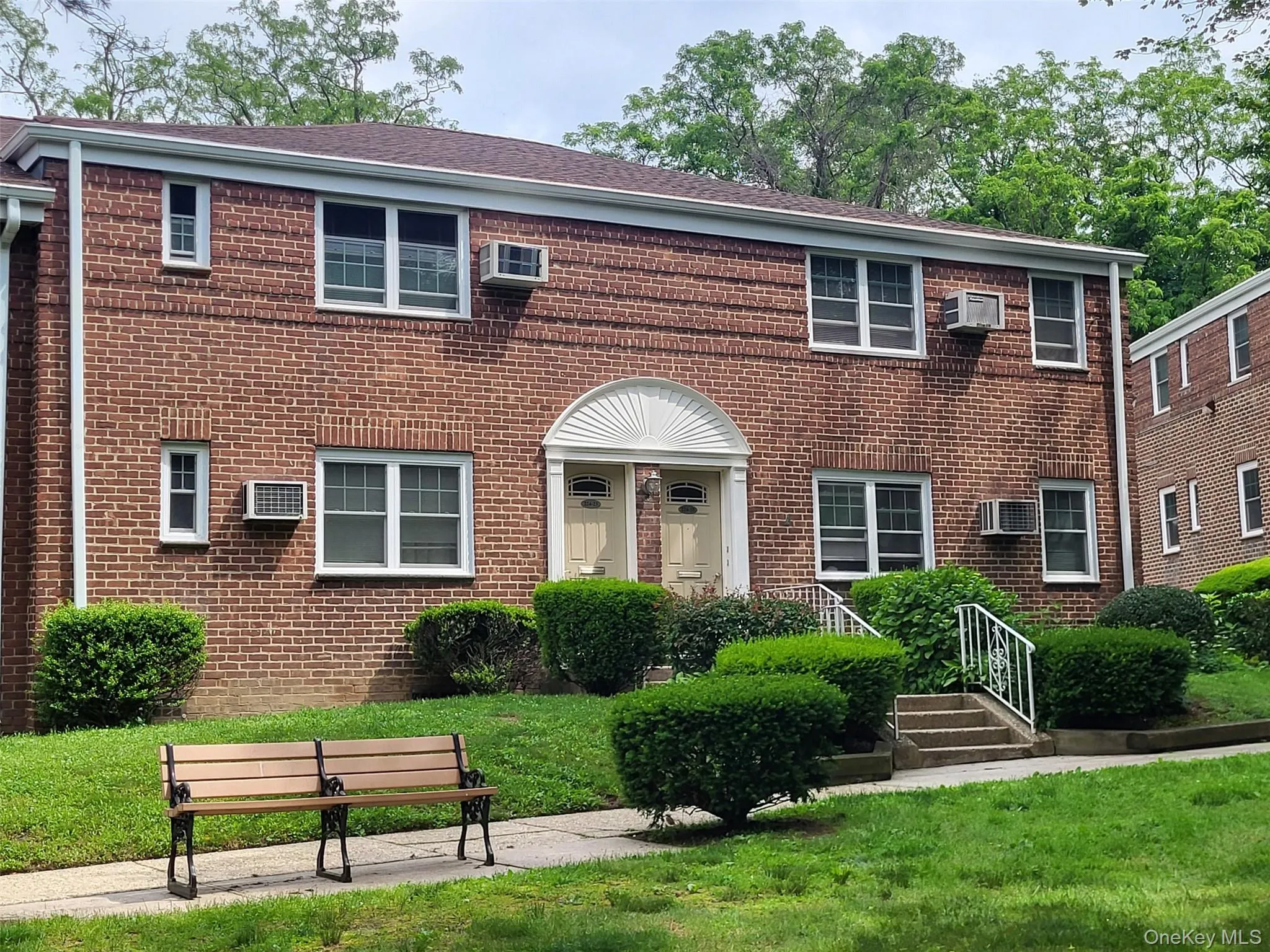 View of front facade featuring an AC wall unit, brick siding, and a front lawn View of front facade featuring an AC wall unit, brick siding, and a front lawn