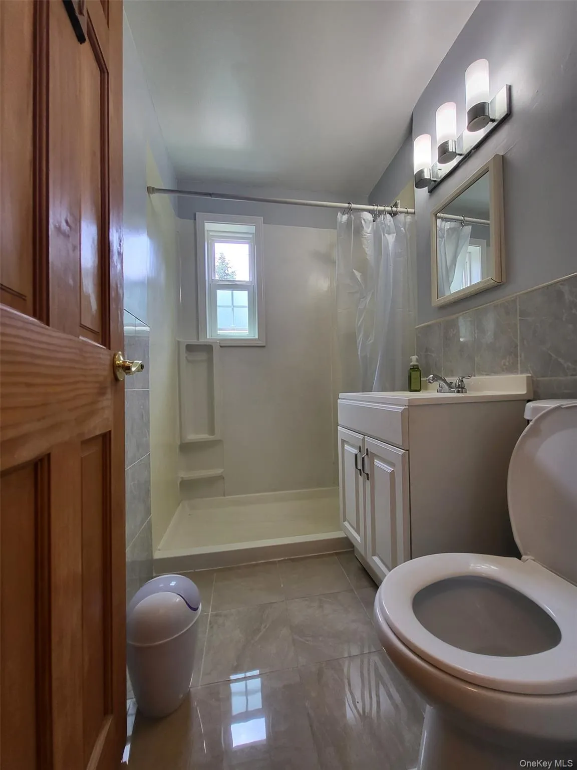 Full bath featuring tile walls, vanity, and a shower with curtain Full bath featuring tile walls, vanity, and a shower with curtain