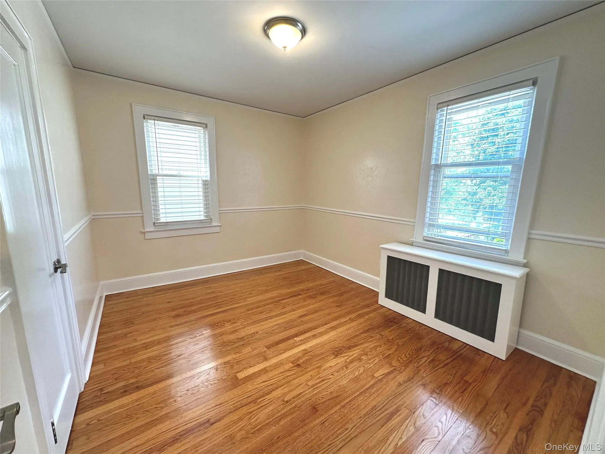 Empty room with radiator heating unit, light wood finished floors, and healthy amount of natural light Empty room with radiator heating unit, light wood finished floors, and healthy amount of natural light