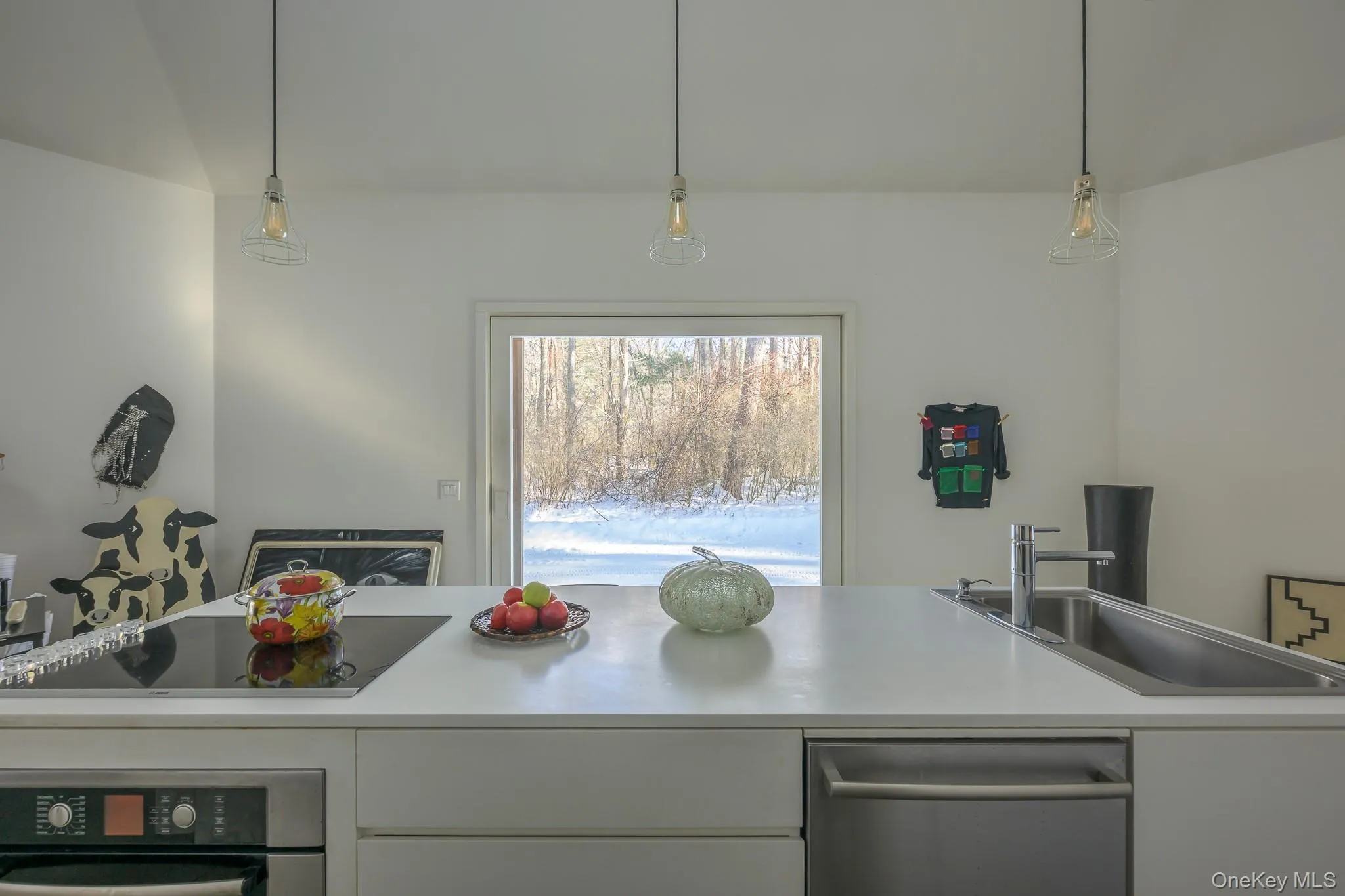 Kitchen featuring light countertops, stainless steel appliances, hanging light fixtures, and white cabinetry Kitchen featuring light countertops, stainless steel appliances, hanging light fixtures, and white cabinetry