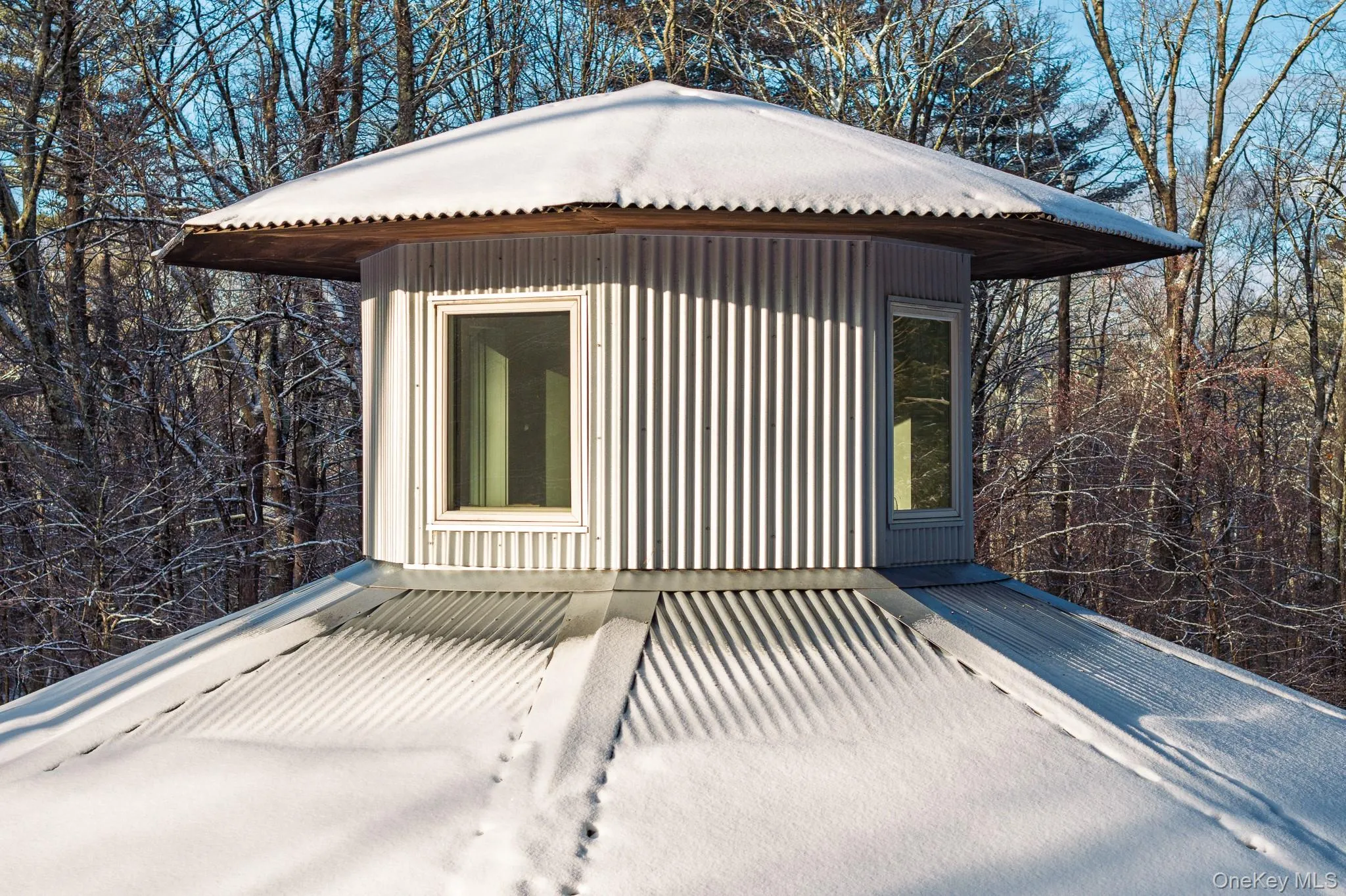 View of home's exterior featuring a metal roof and view of wooded area View of home's exterior featuring a metal roof and view of wooded area