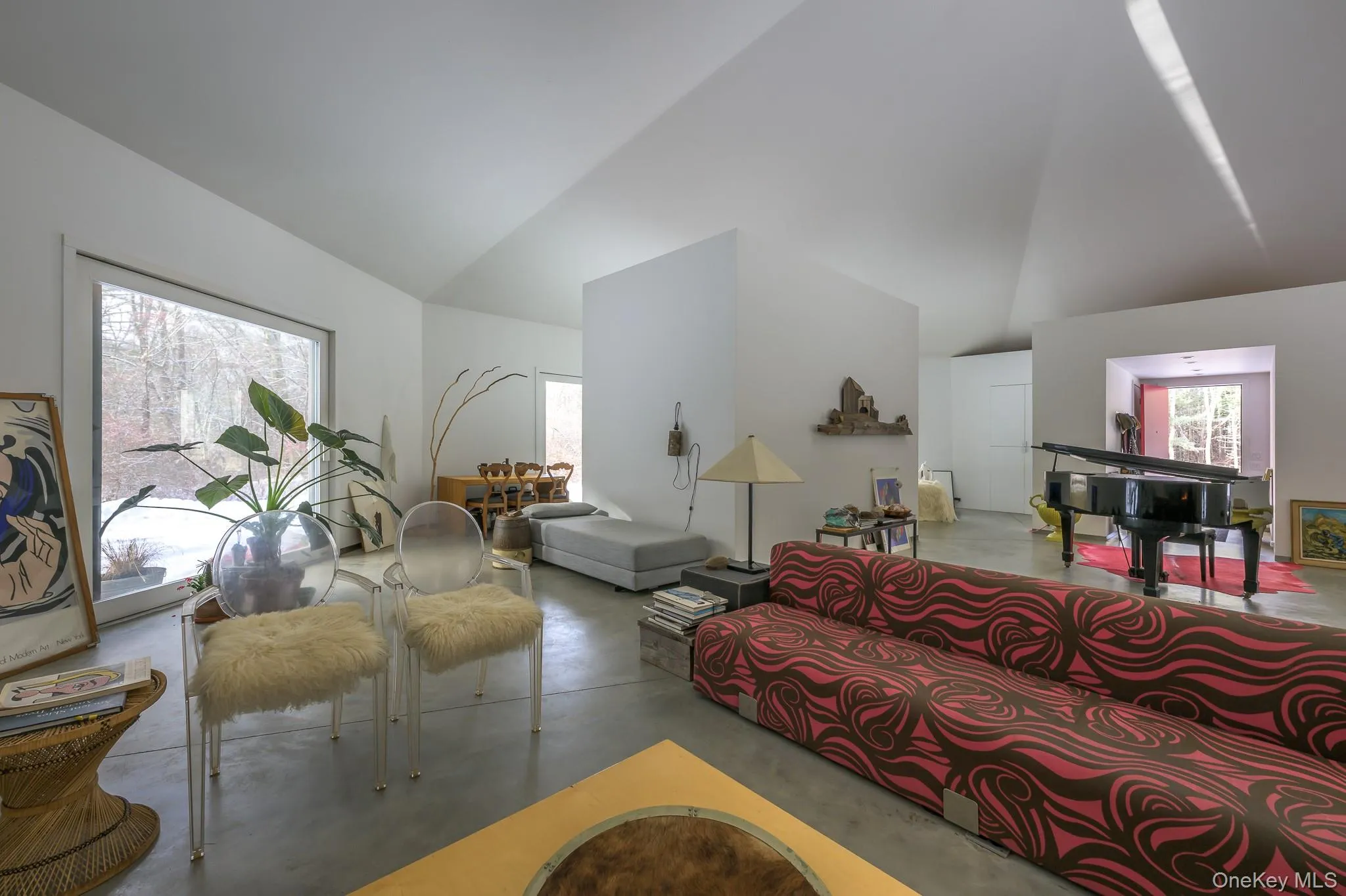 Living room featuring finished concrete floors, high vaulted ceiling, and plenty of natural light Living room featuring finished concrete floors, high vaulted ceiling, and plenty of natural light