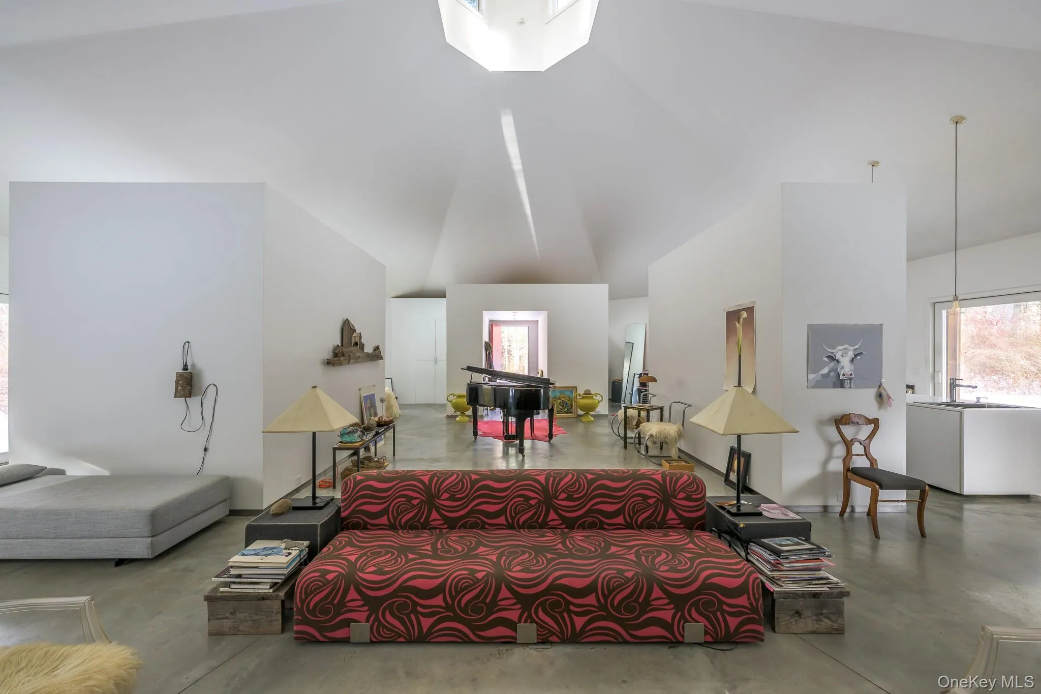 Living area featuring concrete flooring, high vaulted ceiling, and healthy amount of natural light Living area featuring concrete flooring, high vaulted ceiling, and healthy amount of natural light