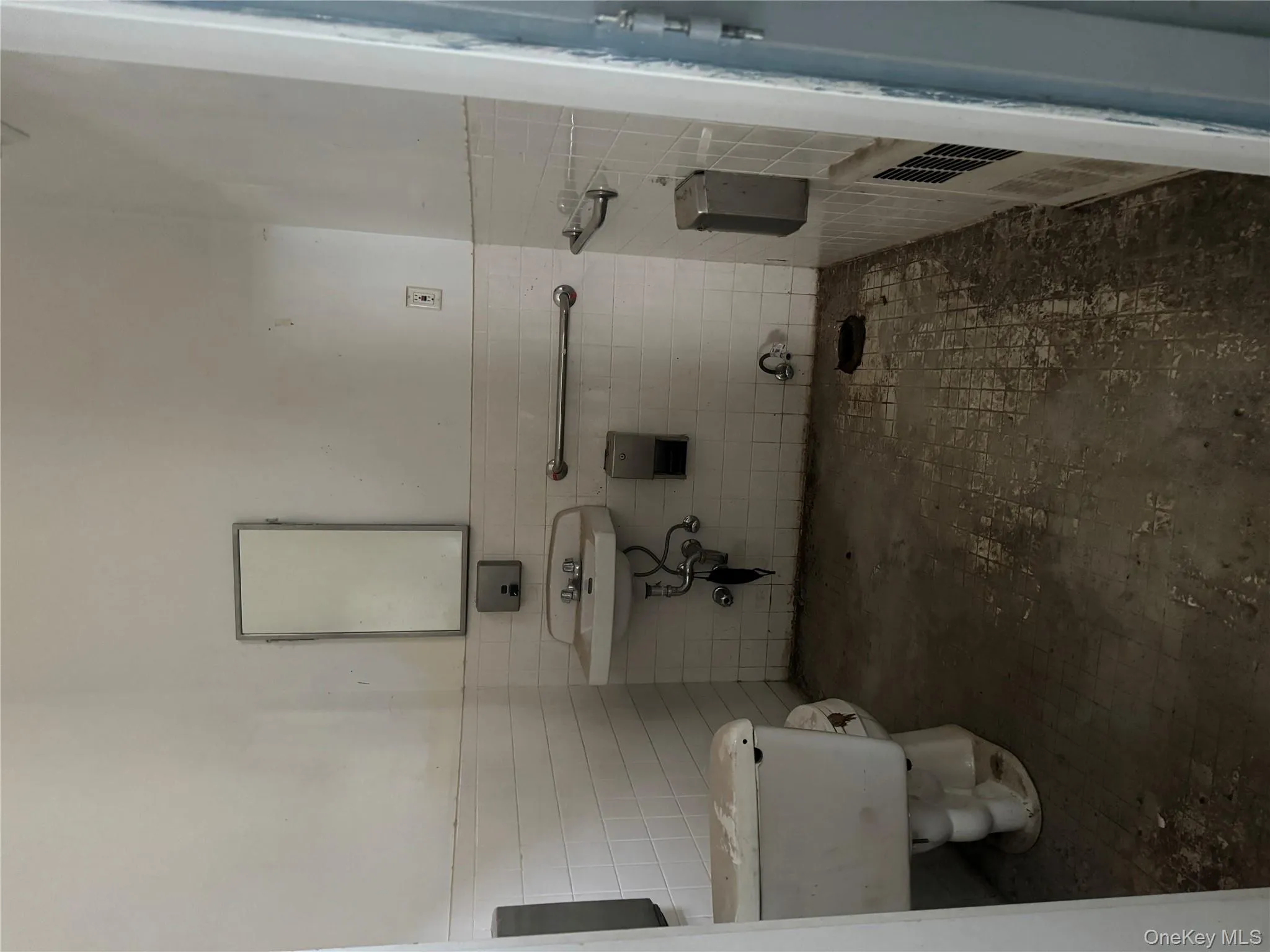 Half bath featuring toilet, tile walls, a wainscoted wall, and a sink Half bath featuring toilet, tile walls, a wainscoted wall, and a sink