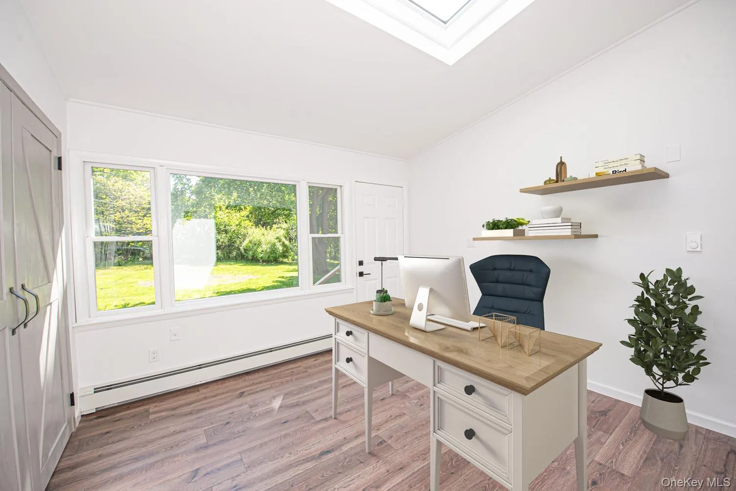 Home office with a baseboard heating unit, light wood finished floors, lofted ceiling, and plenty of natural light Home office with a baseboard heating unit, light wood finished floors, lofted ceiling, and plenty of natural light