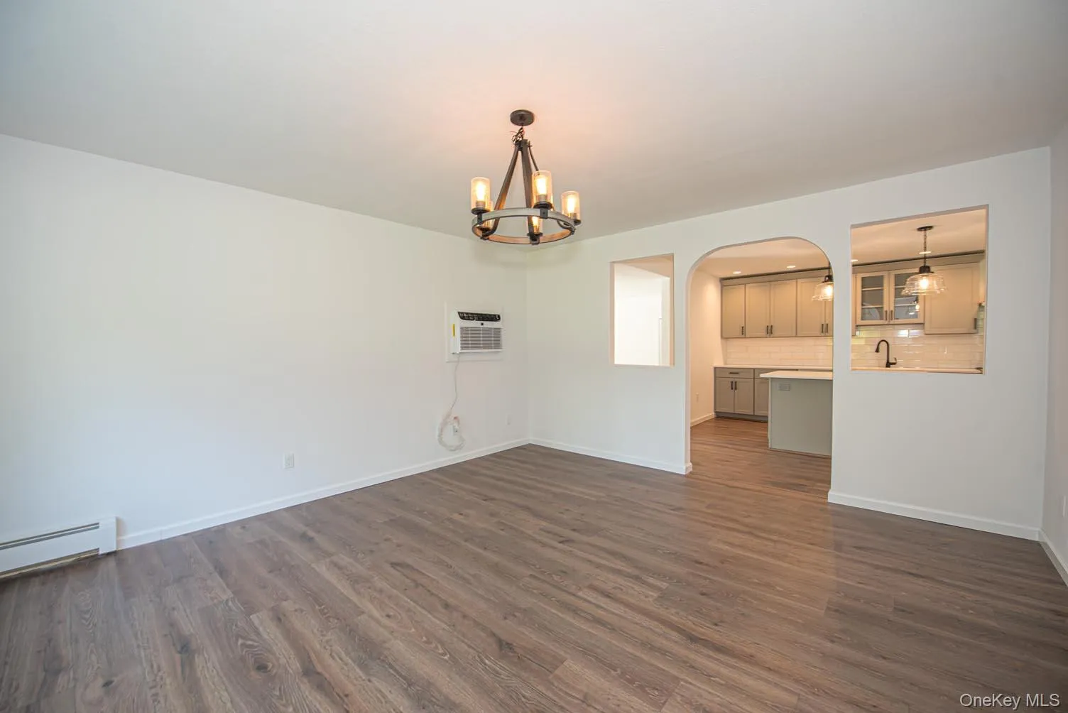 Unfurnished dining area featuring dark wood-style flooring, arched walkways, and a chandelier Unfurnished dining area featuring dark wood-style flooring, arched walkways, and a chandelier
