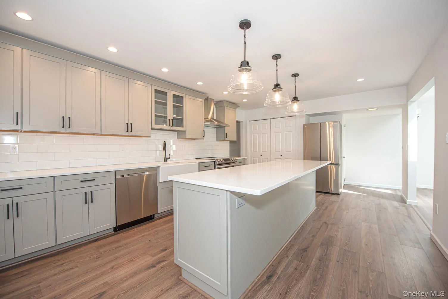 Kitchen with gray cabinets, stainless steel appliances, glass insert cabinets, hanging light fixtures, and recessed lighting Kitchen with gray cabinets, stainless steel appliances, glass insert cabinets, hanging light fixtures, and recessed lighting