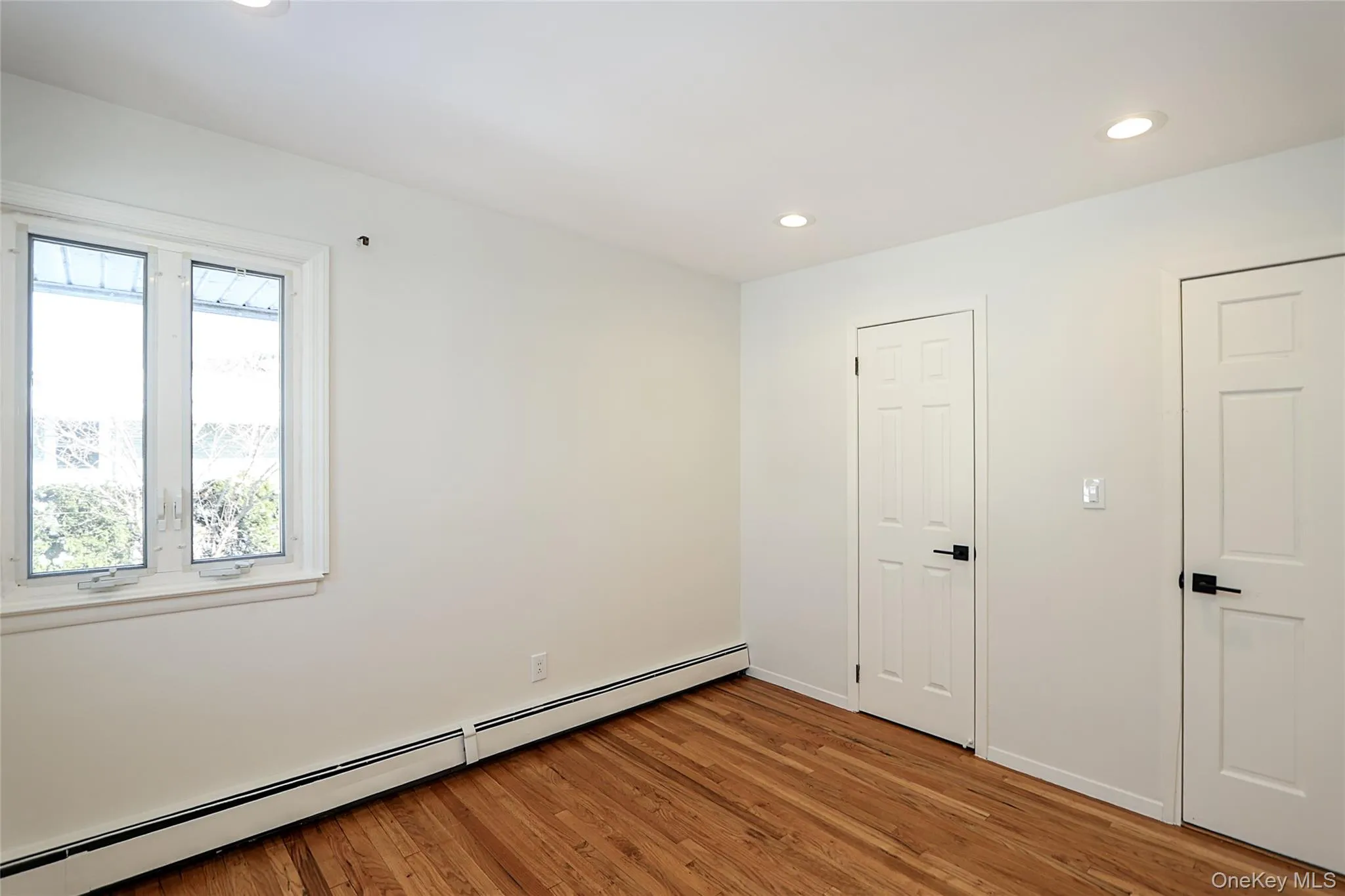Empty room with a baseboard radiator, recessed lighting, and light wood-type flooring Empty room with a baseboard radiator, recessed lighting, and light wood-type flooring