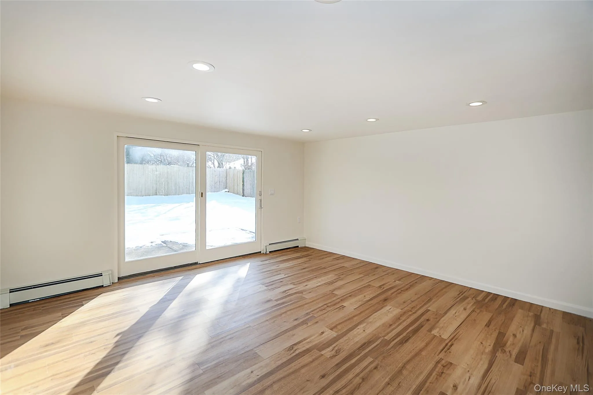 Empty room with recessed lighting, a baseboard radiator, and light wood-style flooring Empty room with recessed lighting, a baseboard radiator, and light wood-style flooring