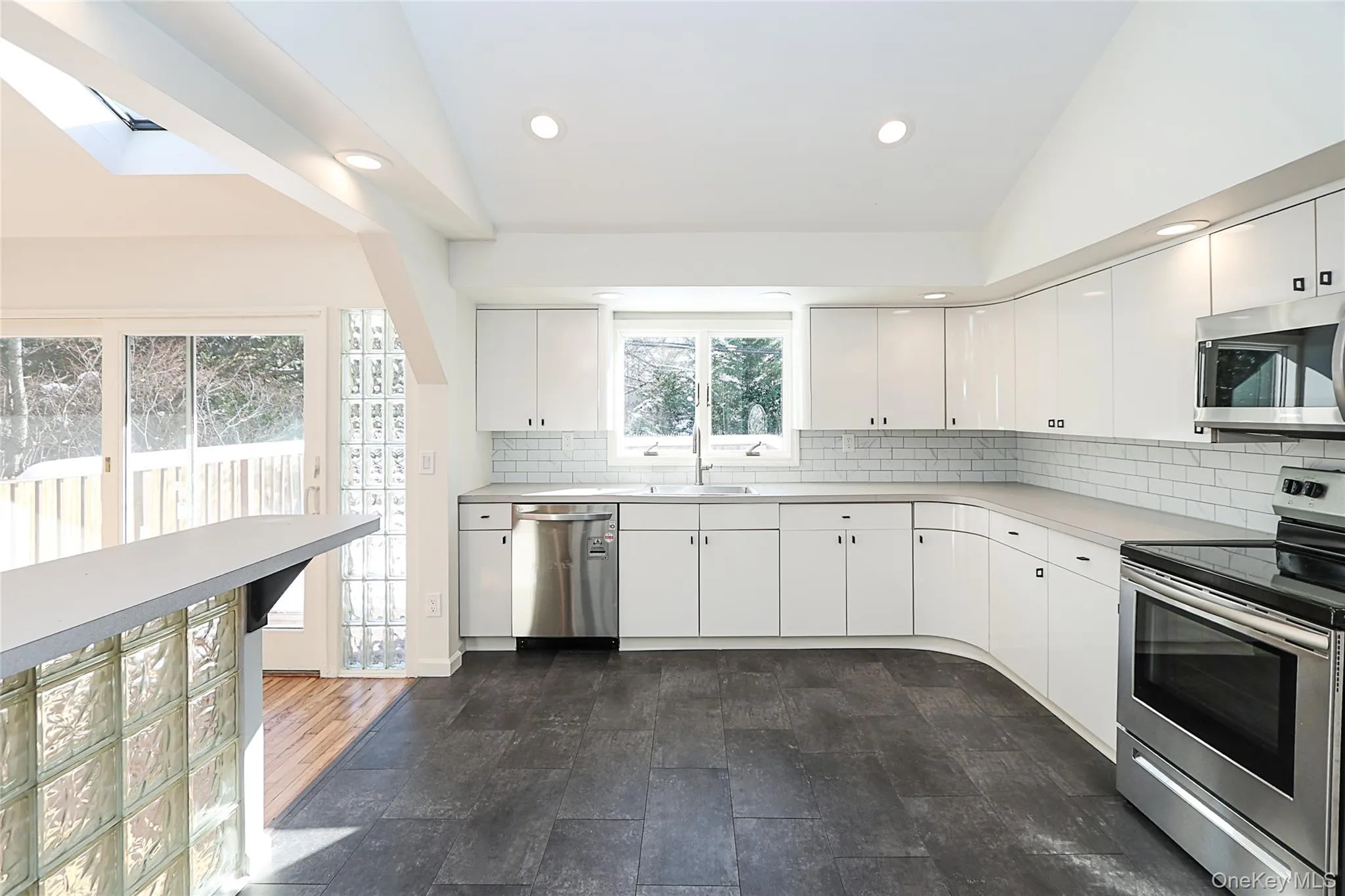Kitchen featuring stainless steel appliances, light countertops, vaulted ceiling, tasteful backsplash, and recessed lighting Kitchen featuring stainless steel appliances, light countertops, vaulted ceiling, tasteful backsplash, and recessed lighting