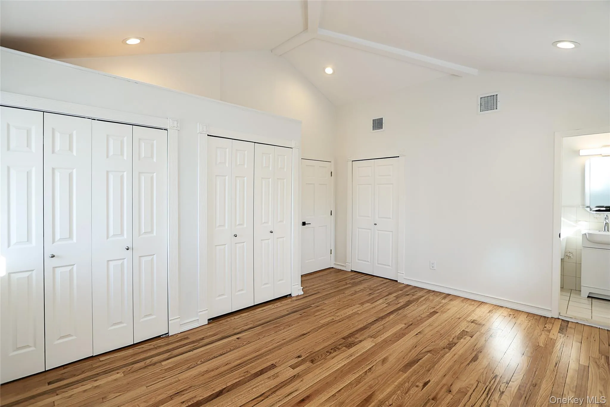 Unfurnished bedroom with multiple closets, light wood-style flooring, beamed ceiling, recessed lighting, and high vaulted ceiling Unfurnished bedroom with multiple closets, light wood-style flooring, beamed ceiling, recessed lighting, and high vaulted ceiling