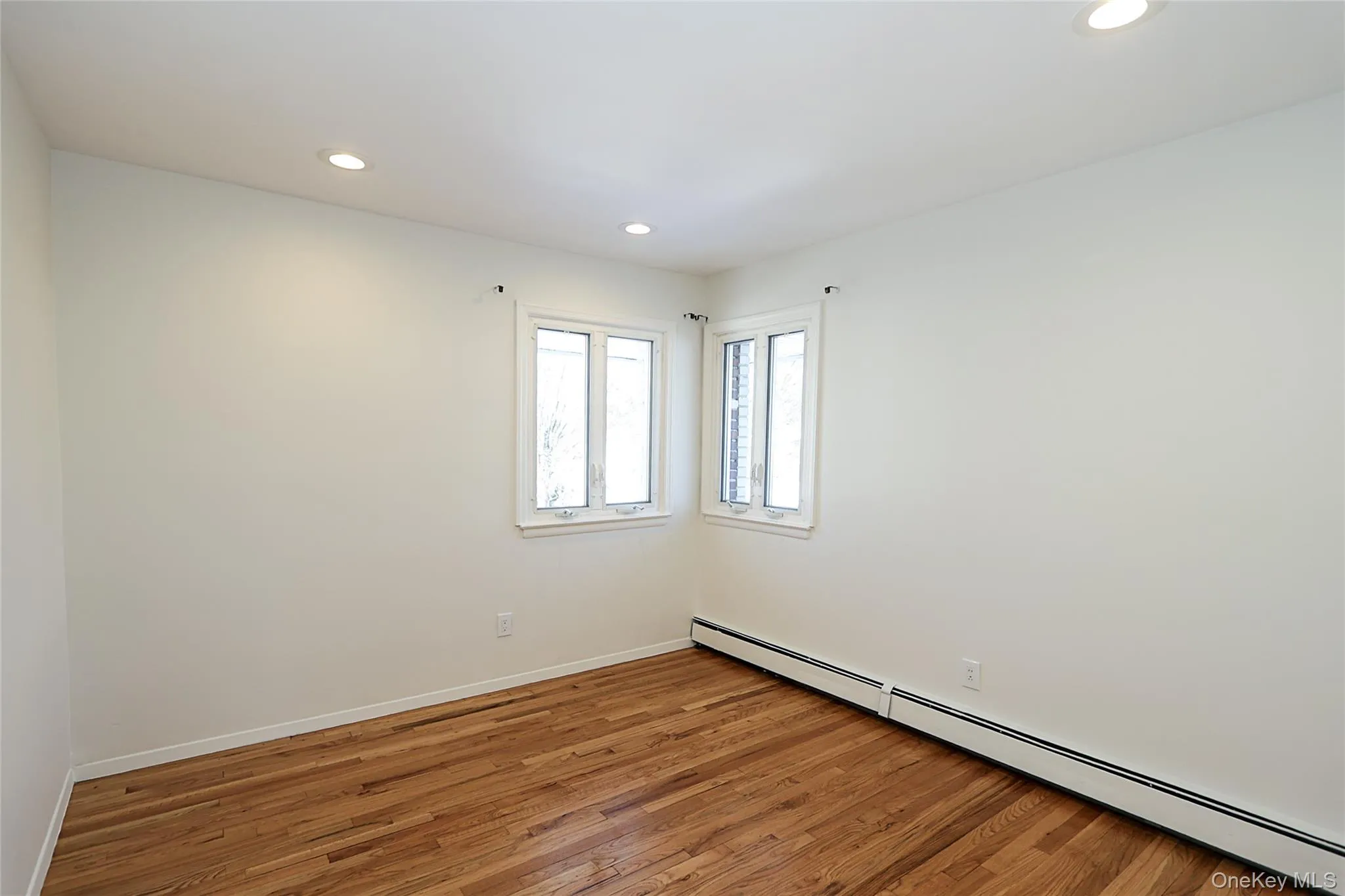 Empty room with a baseboard heating unit, hardwood / wood-style flooring, and recessed lighting Empty room with a baseboard heating unit, hardwood / wood-style flooring, and recessed lighting