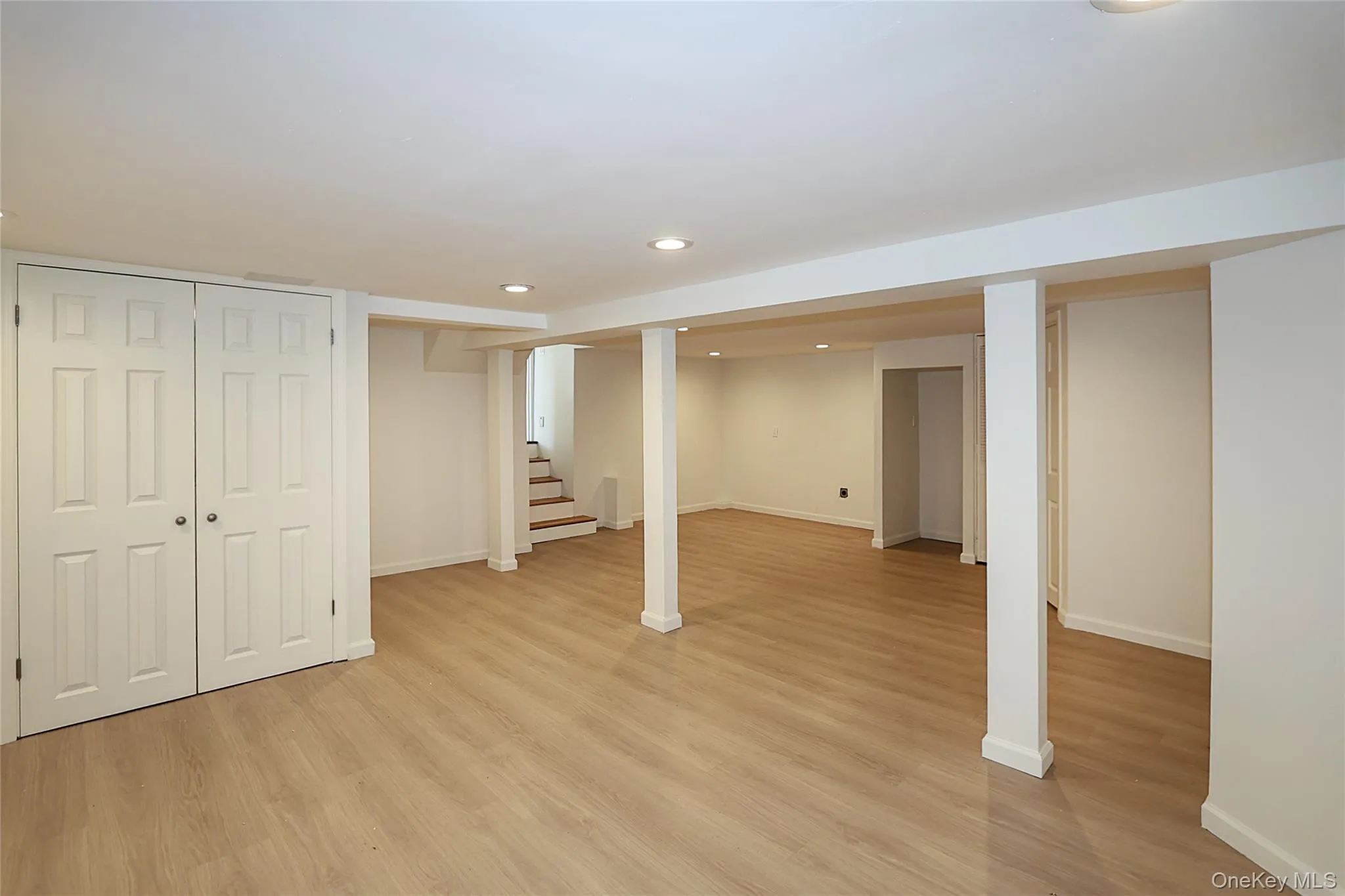 Finished basement with light wood-type flooring, recessed lighting, and stairway Finished basement with light wood-type flooring, recessed lighting, and stairway