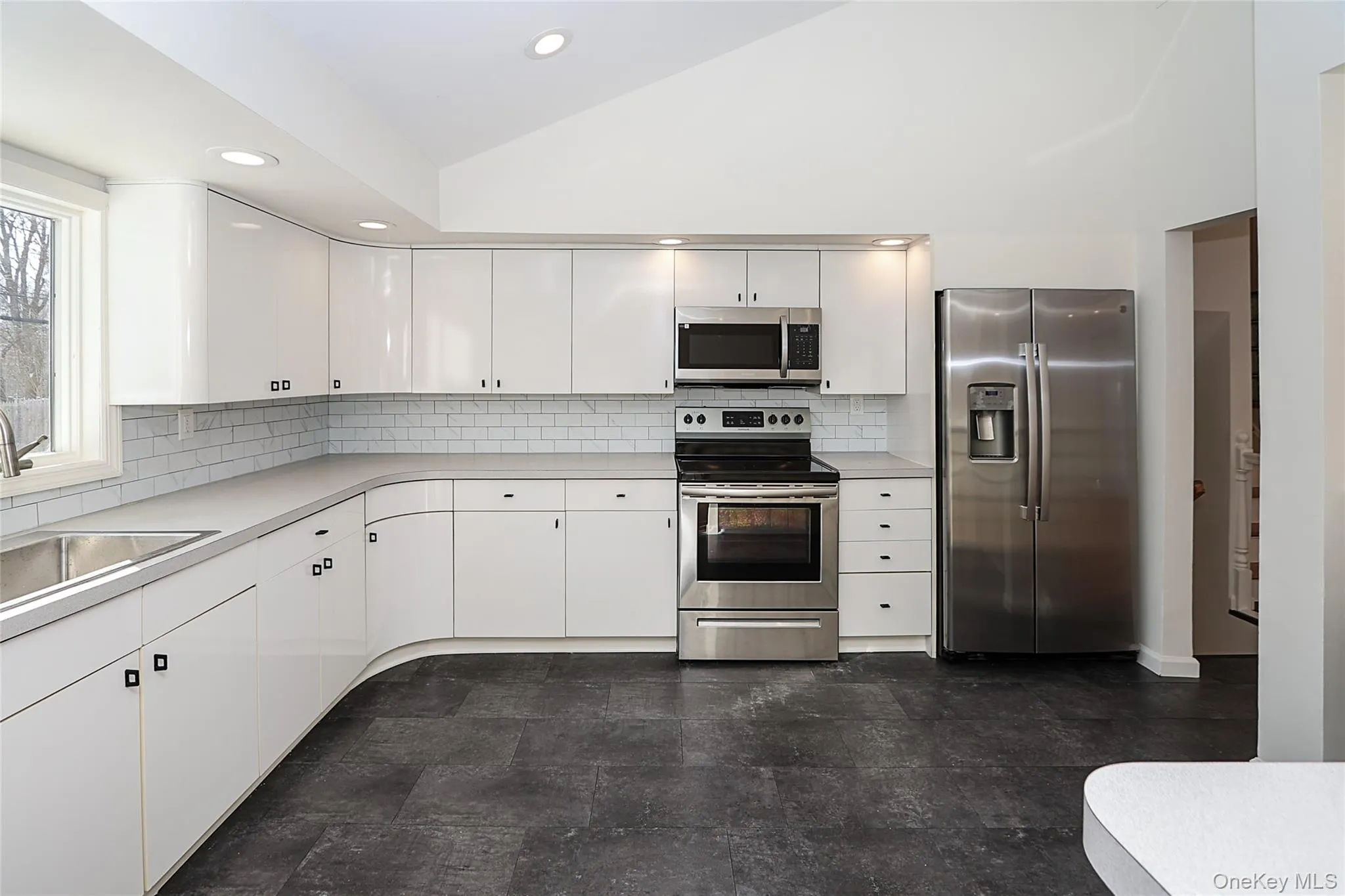 Kitchen with appliances with stainless steel finishes, light countertops, white cabinetry, decorative backsplash, and recessed lighting Kitchen with appliances with stainless steel finishes, light countertops, white cabinetry, decorative backsplash, and recessed lighting