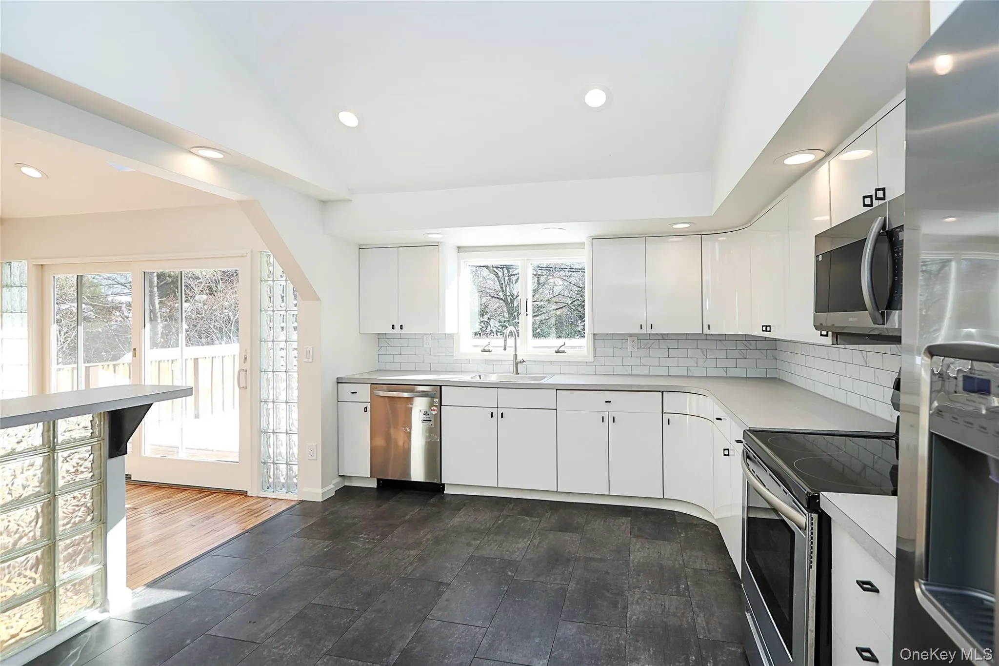 Kitchen with appliances with stainless steel finishes, light countertops, recessed lighting, backsplash, and white cabinets Kitchen with appliances with stainless steel finishes, light countertops, recessed lighting, backsplash, and white cabinets