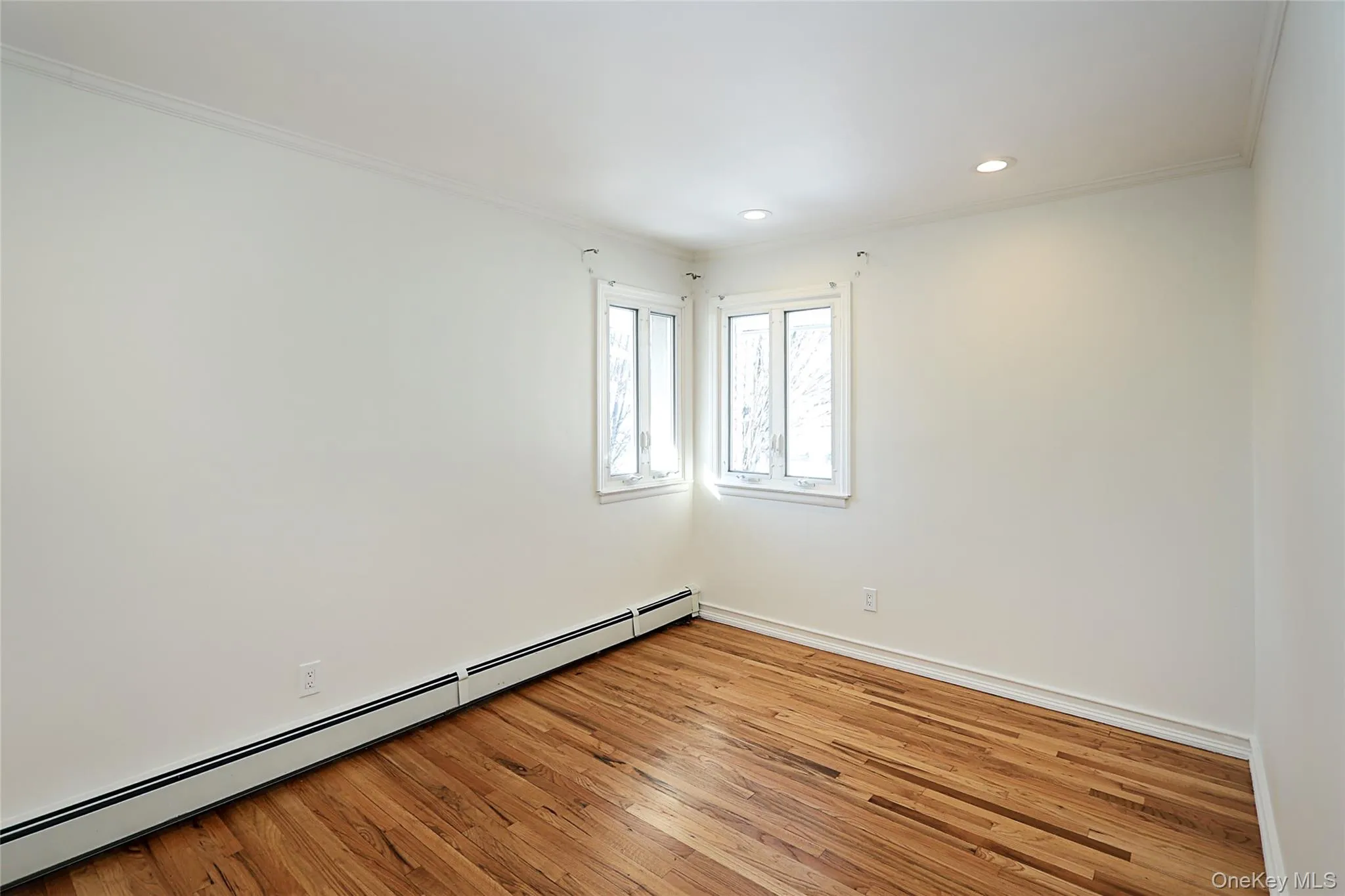 Spare room with a baseboard heating unit, crown molding, hardwood / wood-style flooring, and recessed lighting Spare room with a baseboard heating unit, crown molding, hardwood / wood-style flooring, and recessed lighting