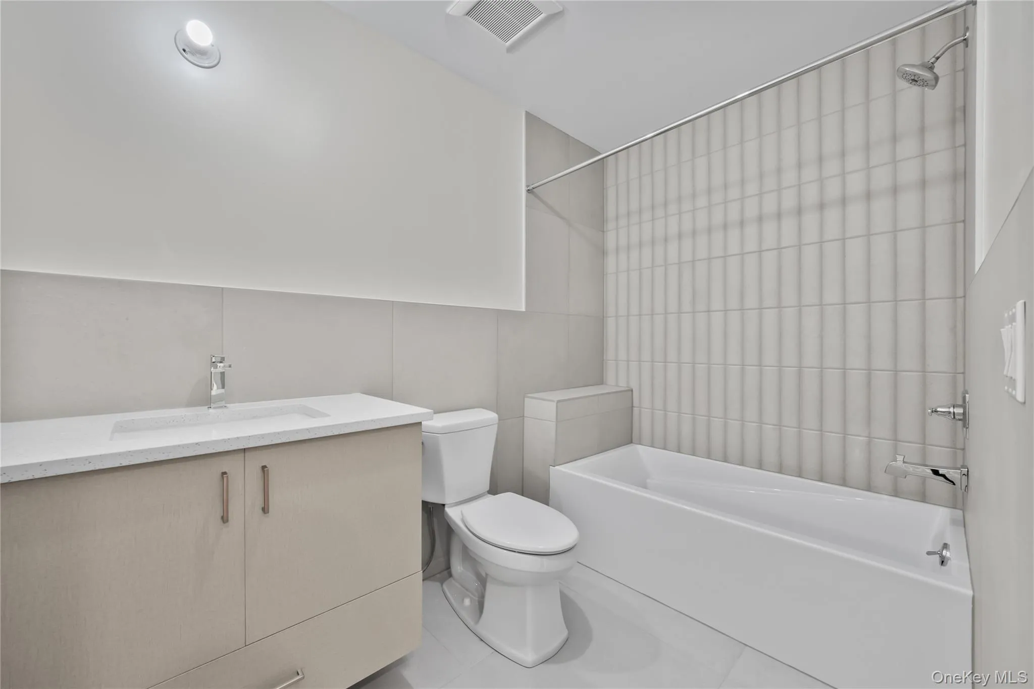 Bathroom featuring vanity, tile walls, tub / shower combination, and tile patterned floors Bathroom featuring vanity, tile walls, tub / shower combination, and tile patterned floors