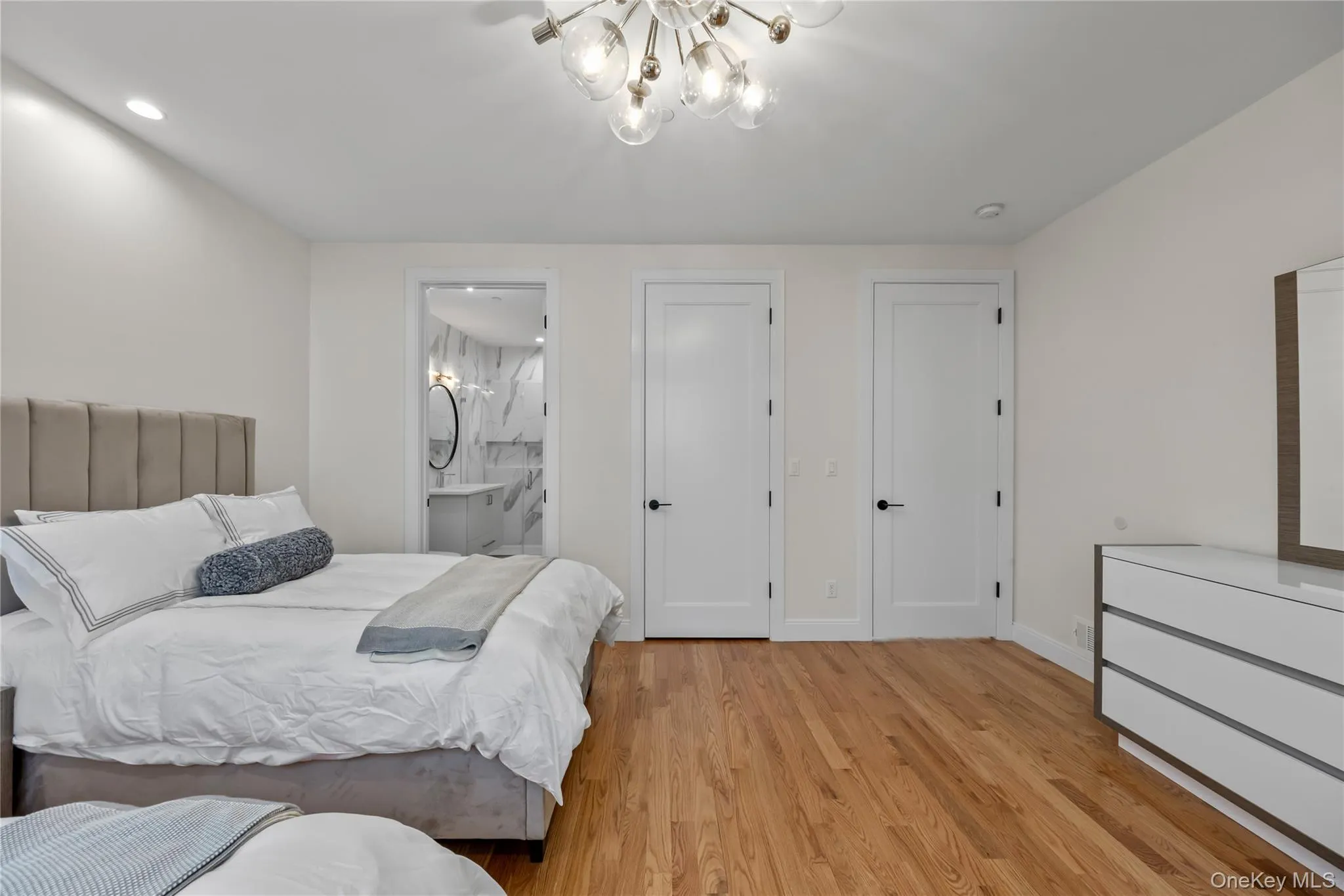 Bedroom with light wood-style flooring, a chandelier, and ensuite bathroom Bedroom with light wood-style flooring, a chandelier, and ensuite bathroom