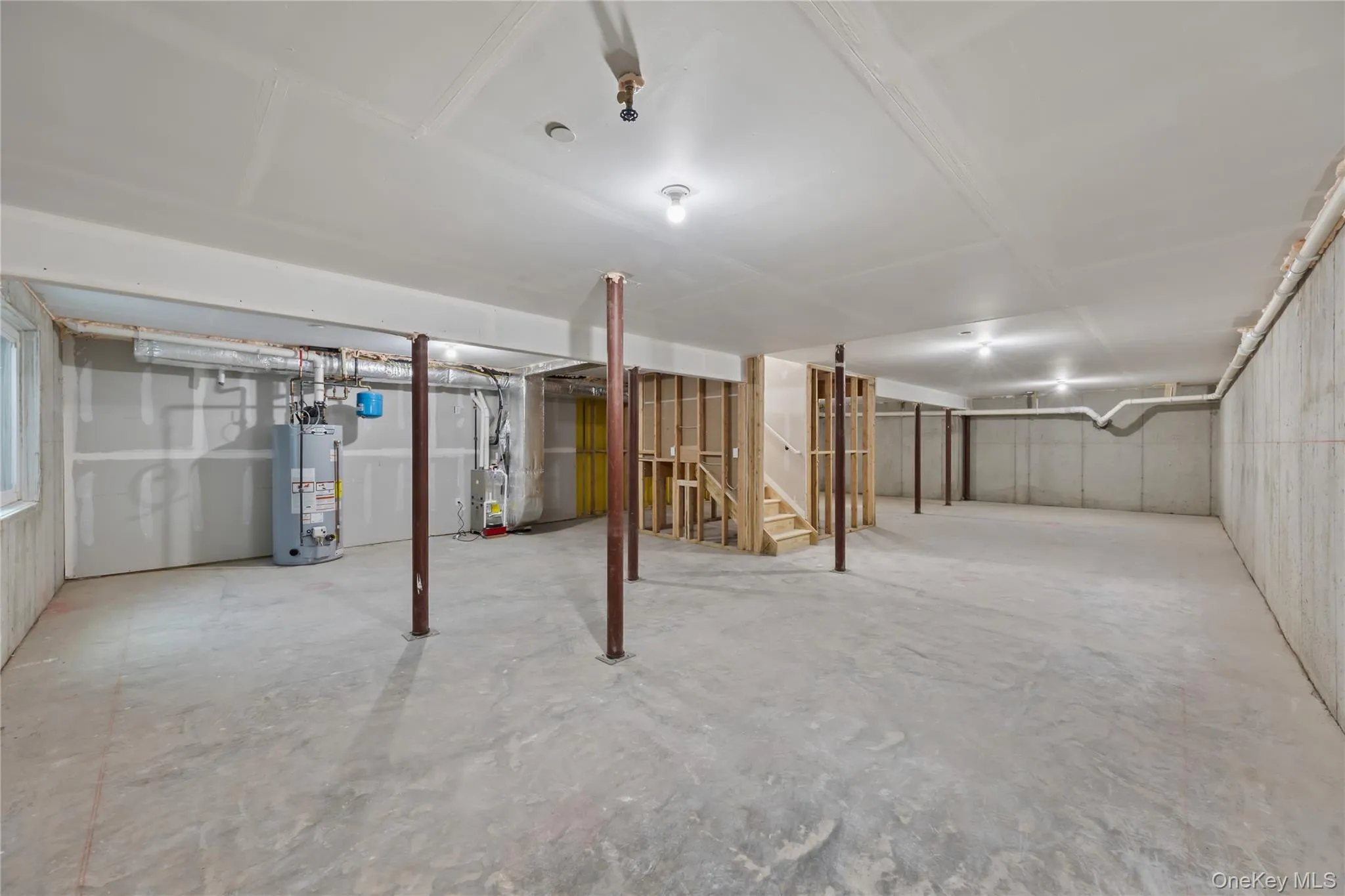 Unfinished below grade area with stairs, water heater, and heating unit Unfinished below grade area with stairs, water heater, and heating unit