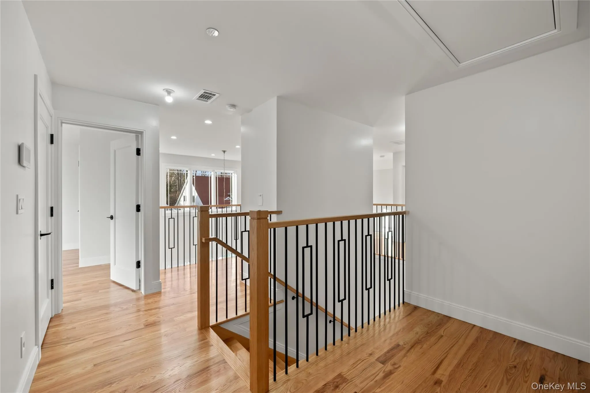 Corridor with an upstairs landing, light wood-style flooring, and recessed lighting Corridor with an upstairs landing, light wood-style flooring, and recessed lighting