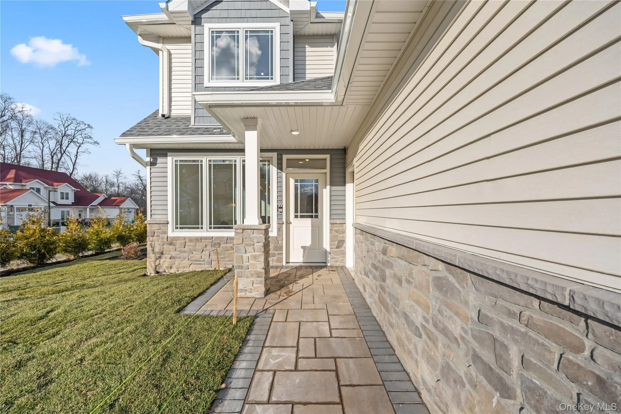 Property entrance featuring a shingled roof, a lawn, and stone siding Property entrance featuring a shingled roof, a lawn, and stone siding