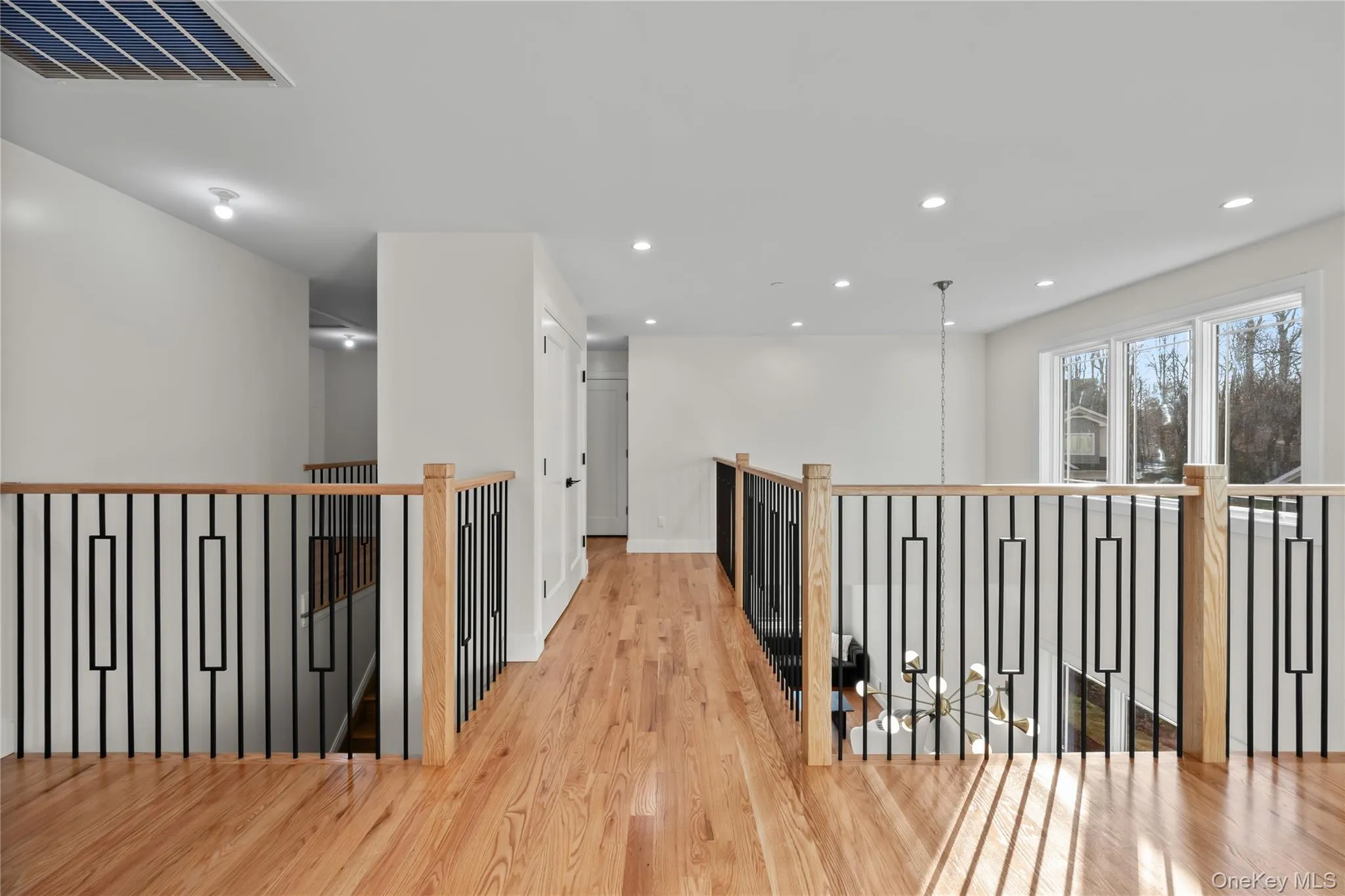 Corridor featuring light wood finished floors, an upstairs landing, and recessed lighting Corridor featuring light wood finished floors, an upstairs landing, and recessed lighting