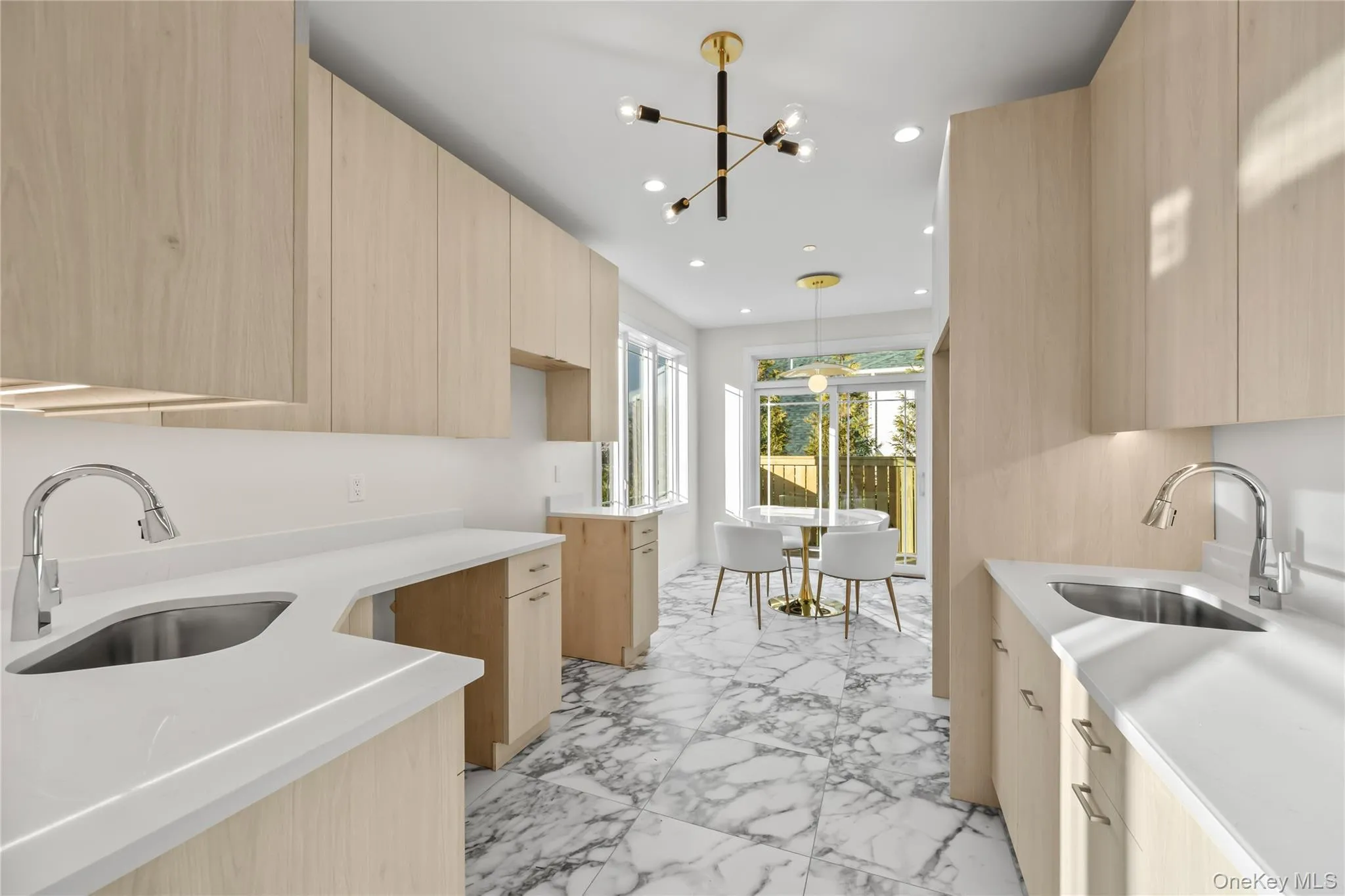Kitchen with light brown cabinets, modern cabinets, light stone countertops, light marble finish flooring, and a chandelier Kitchen with light brown cabinets, modern cabinets, light stone countertops, light marble finish flooring, and a chandelier