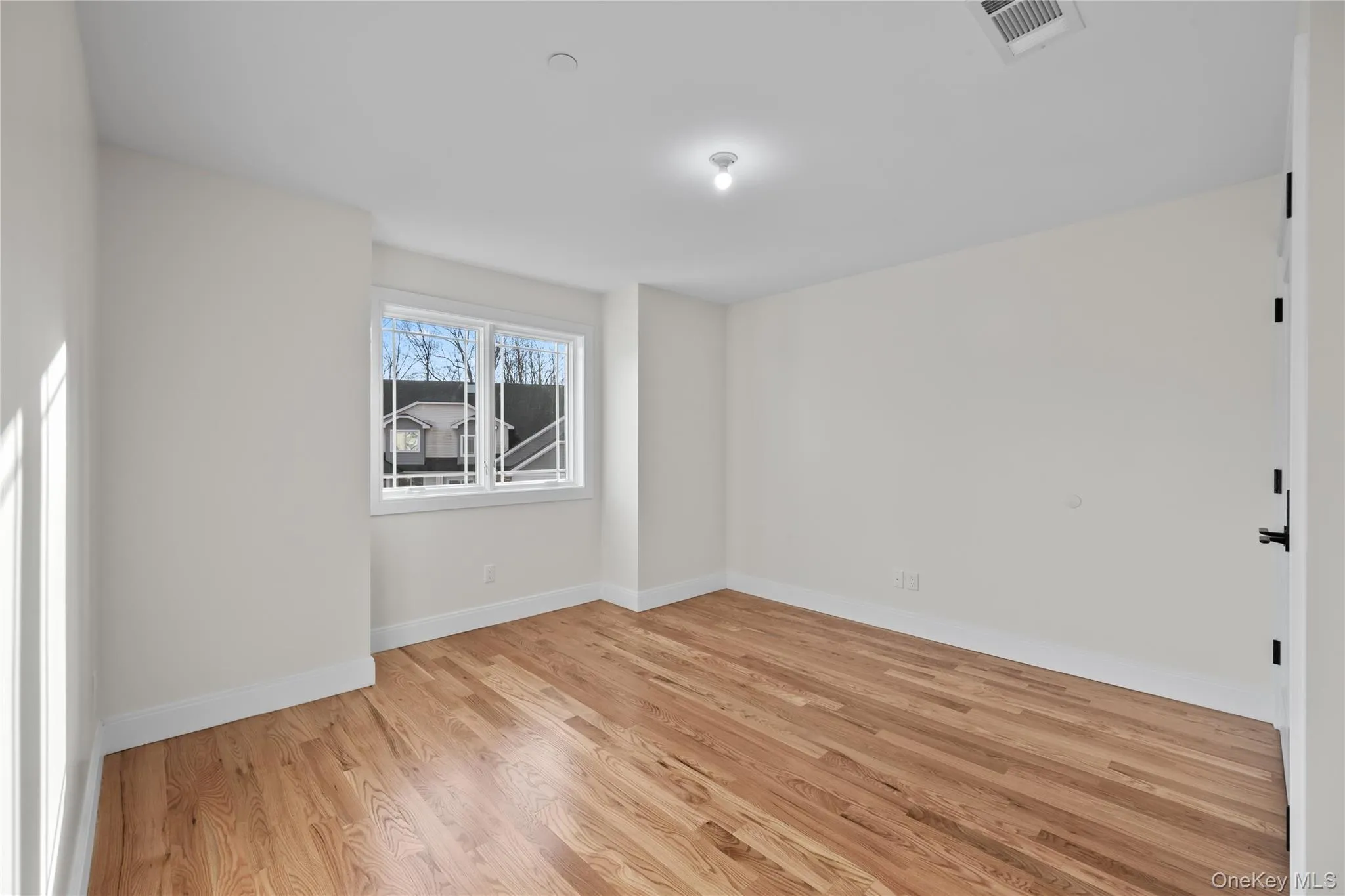 Spare room with light wood finished floors and baseboards Spare room with light wood finished floors and baseboards