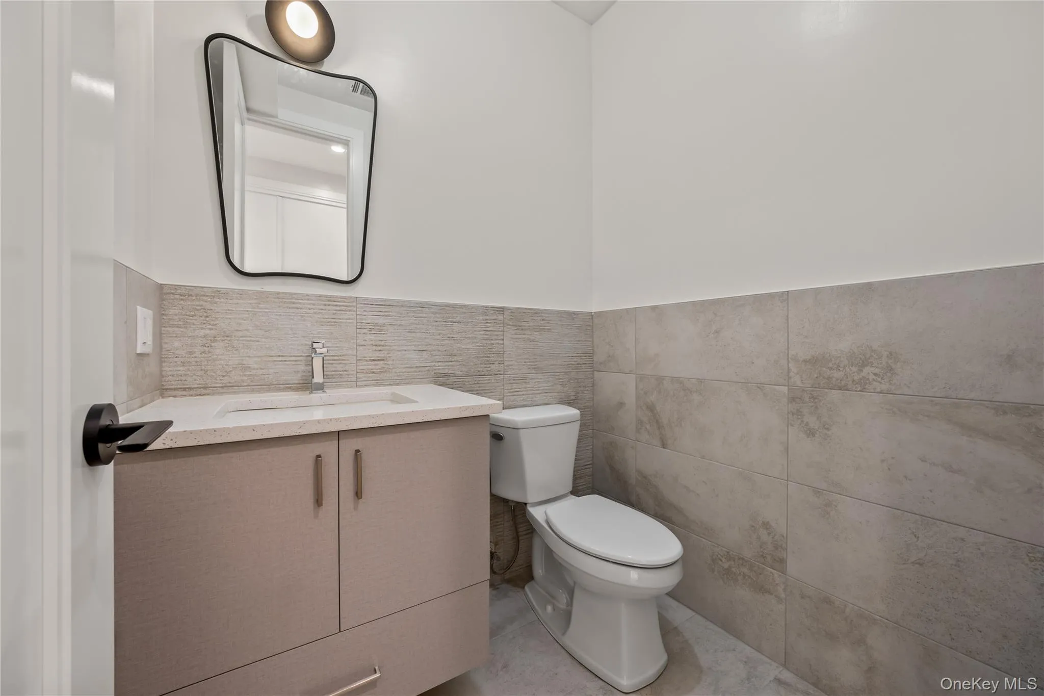 Bathroom with vanity, tile walls, light tile patterned floors, and a wainscoted wall Bathroom with vanity, tile walls, light tile patterned floors, and a wainscoted wall