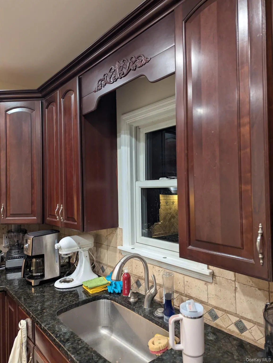 Kitchen featuring dark brown cabinetry, dark stone countertops, and tasteful backsplash Kitchen featuring dark brown cabinetry, dark stone countertops, and tasteful backsplash